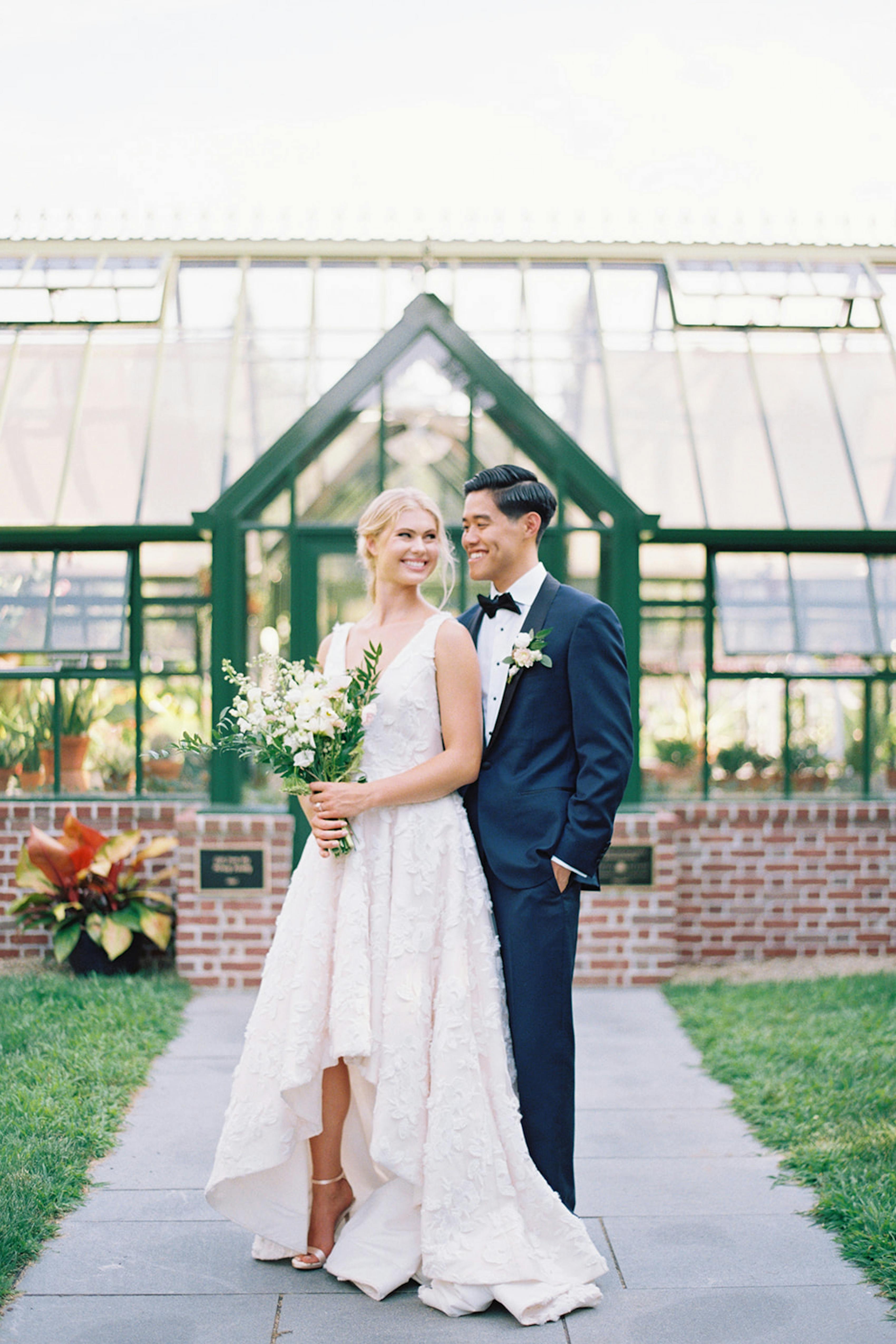 Sustainable wedding venue at greenhouse with bride and groom in navy tuxedo