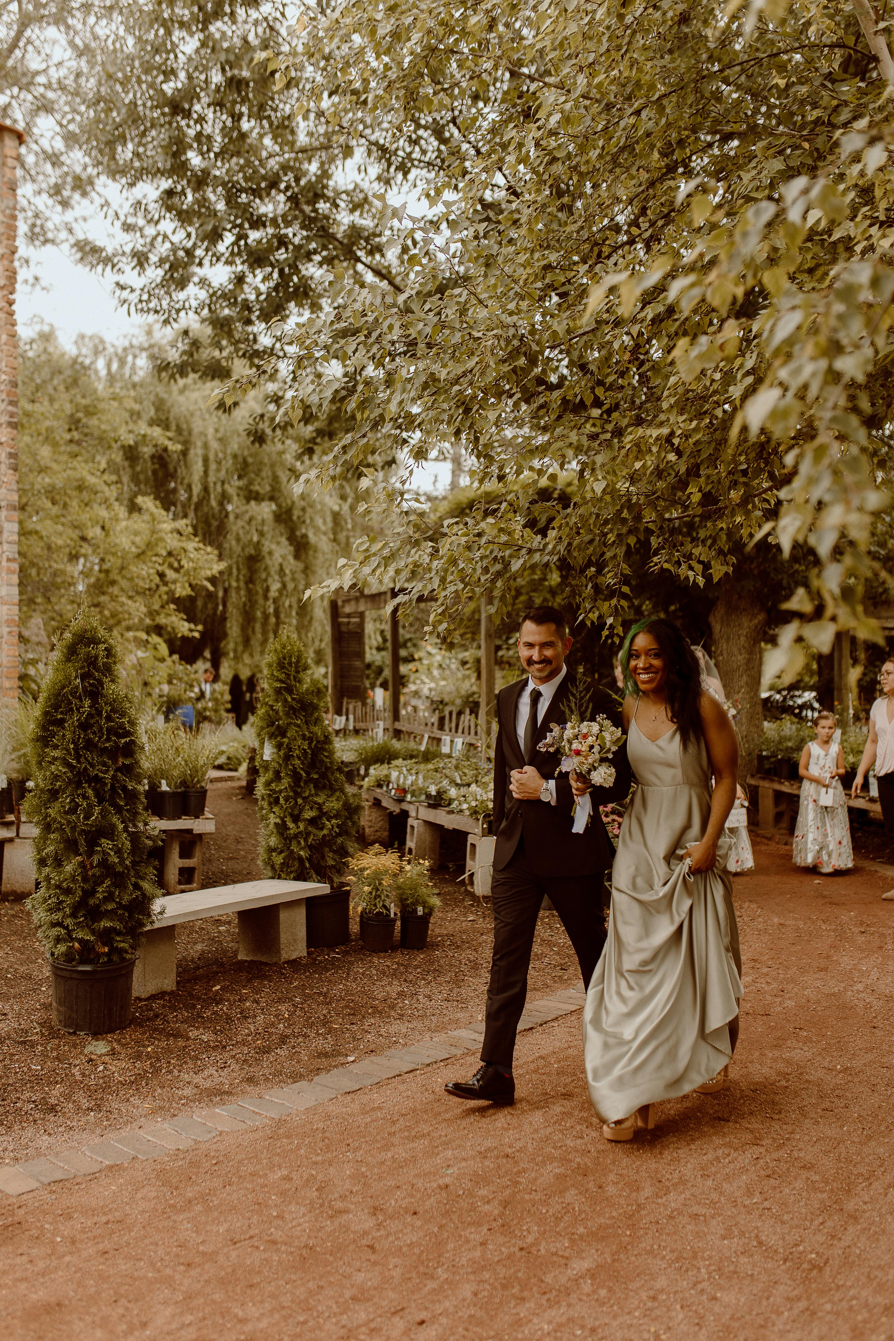 Park wedding venue with charcoal grey groomsman suit and sage green bridesmaid dress