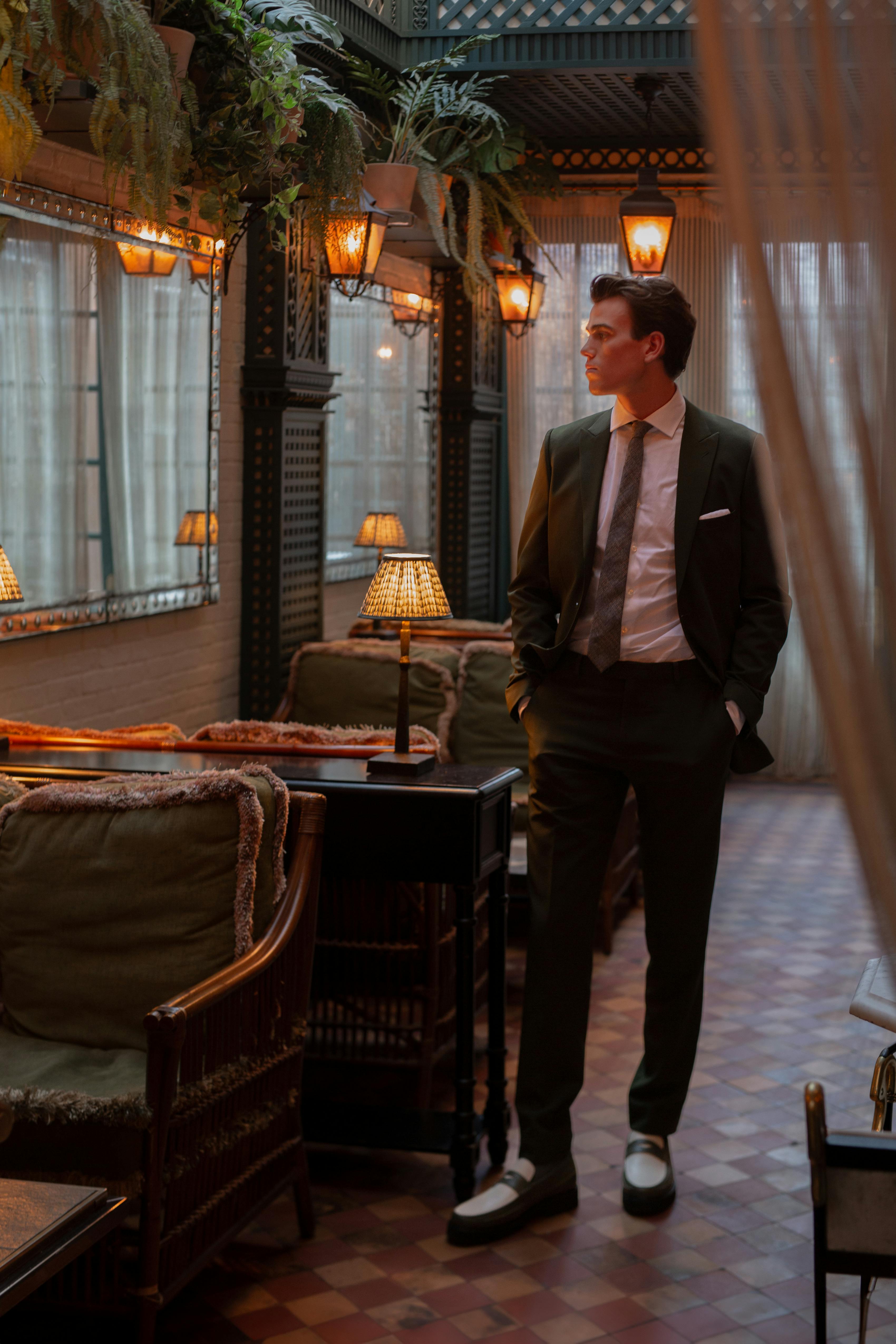 Man at cocktail bar wearing trendy olive green suit with olive loafers