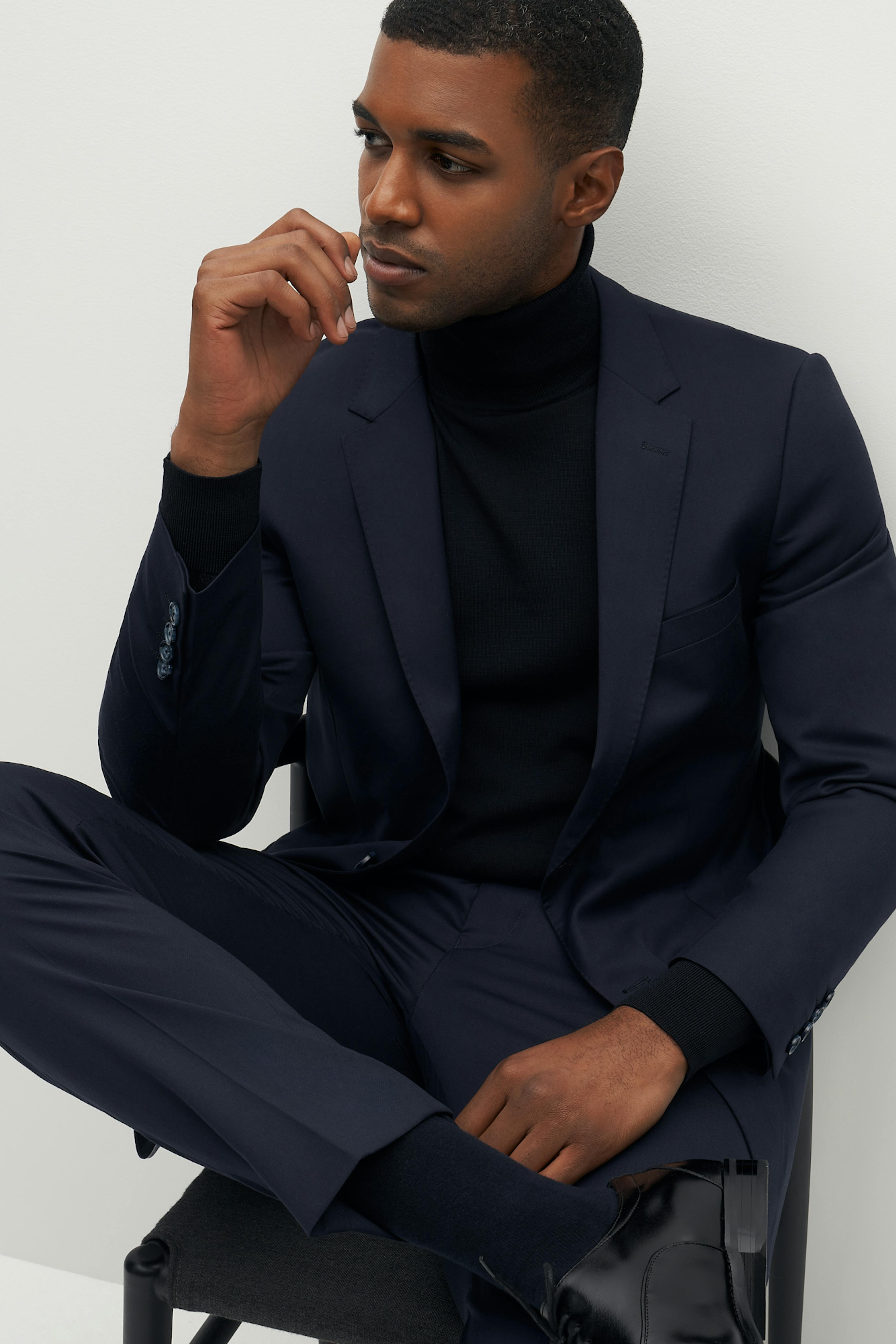 Man wearing navy suit and black turtleneck for smart casual new year's eve cocktail party