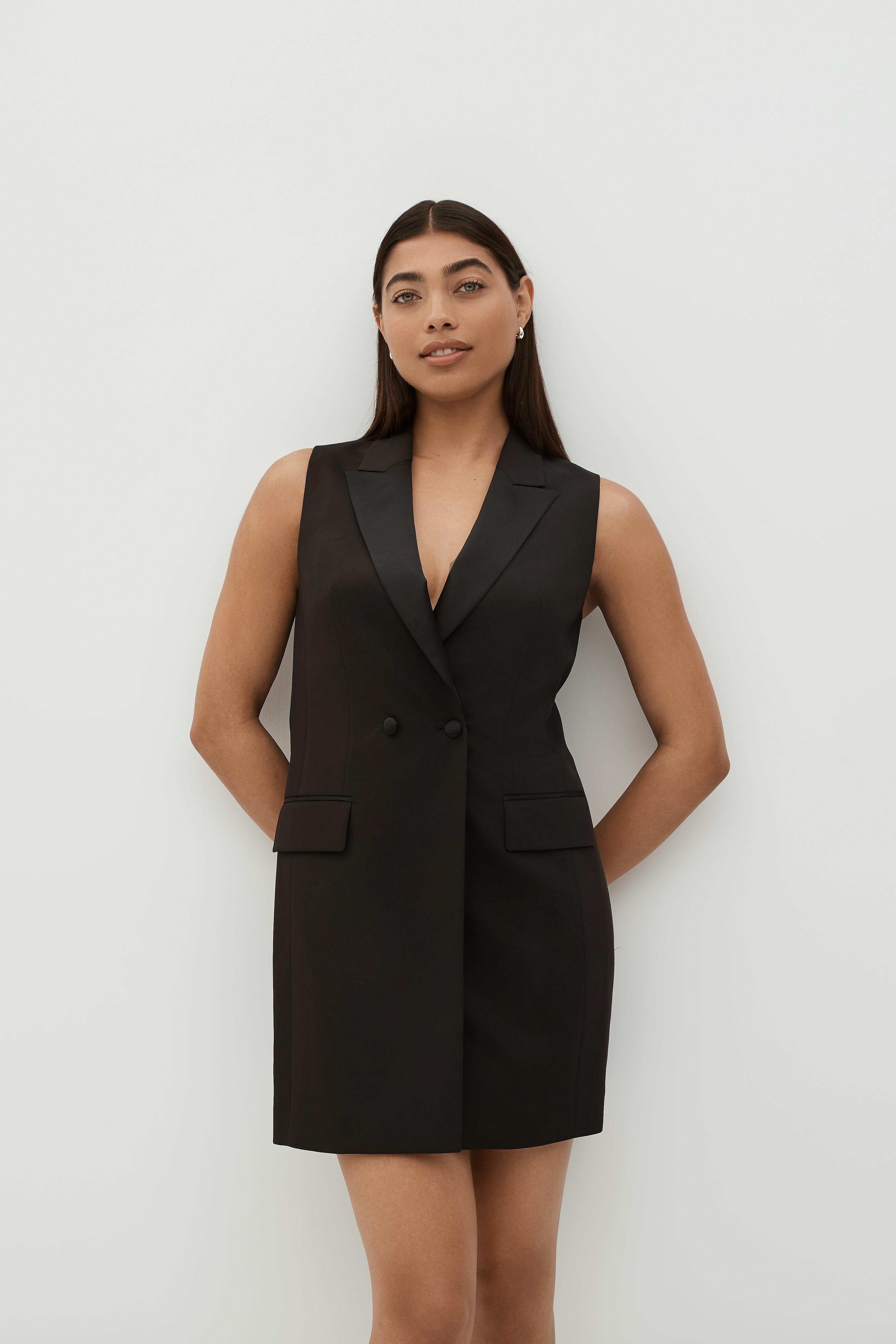 Woman wearing sleeveless black tuxedo dress for holiday outfit on New Year's Eve