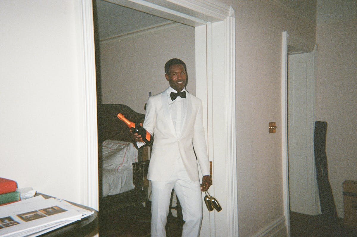 Man wearing white tuxedo holding champagne for new year's eve outfit at black tie party