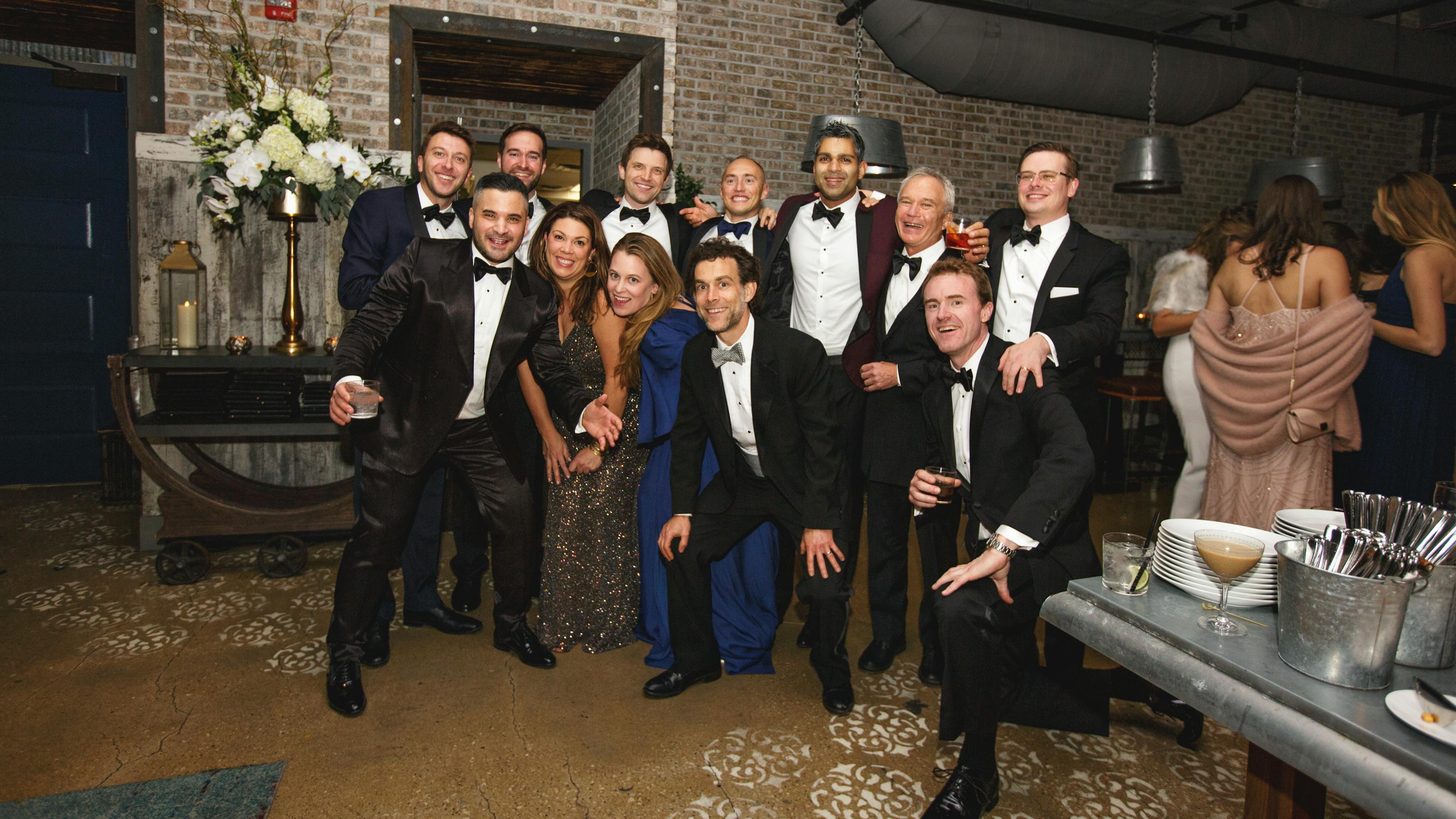 Guests at black tie winter wedding wearing tuxedos and formal gowns