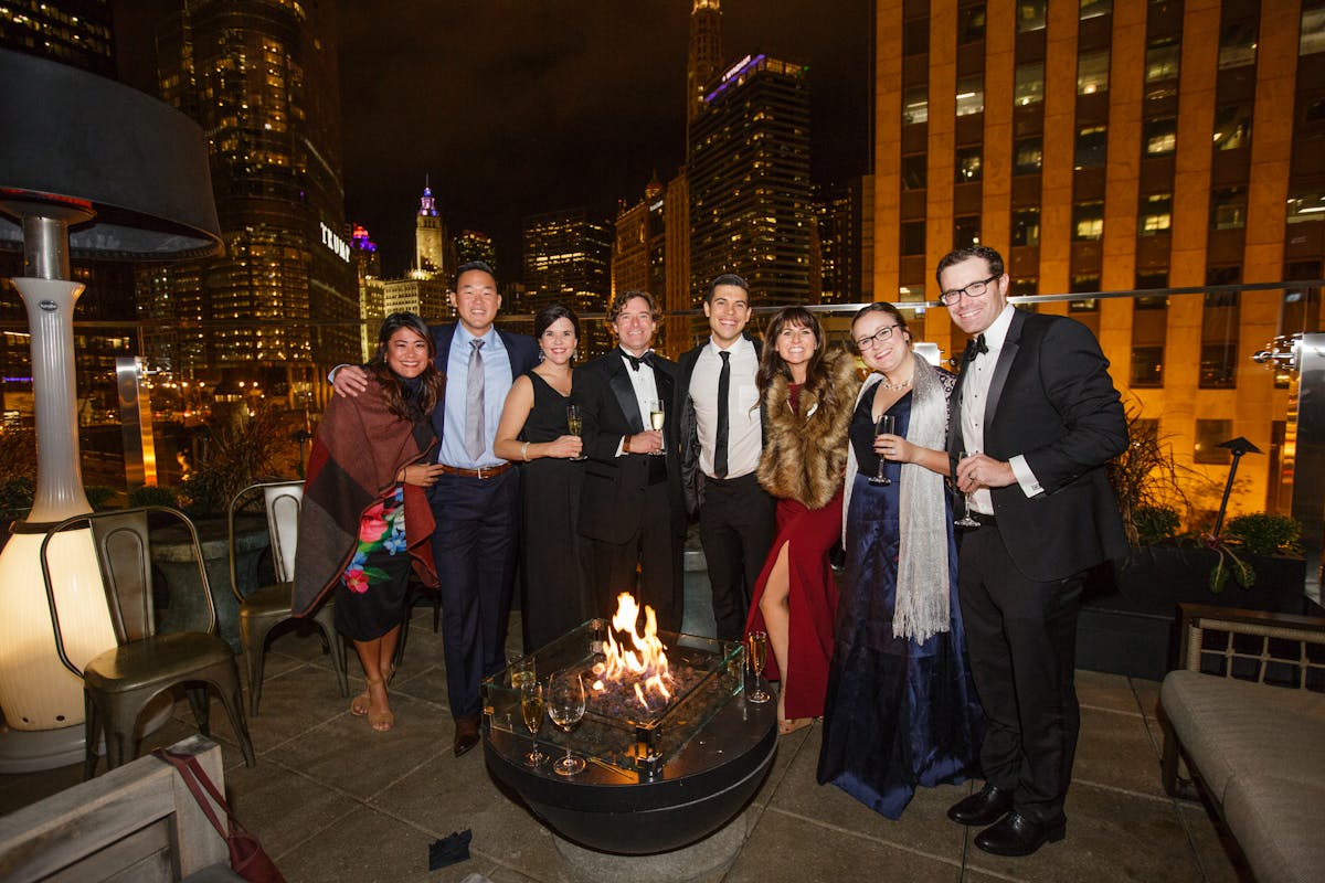 Winter wedding guest outfits with suits, dresses, and shawls in front of city skyline