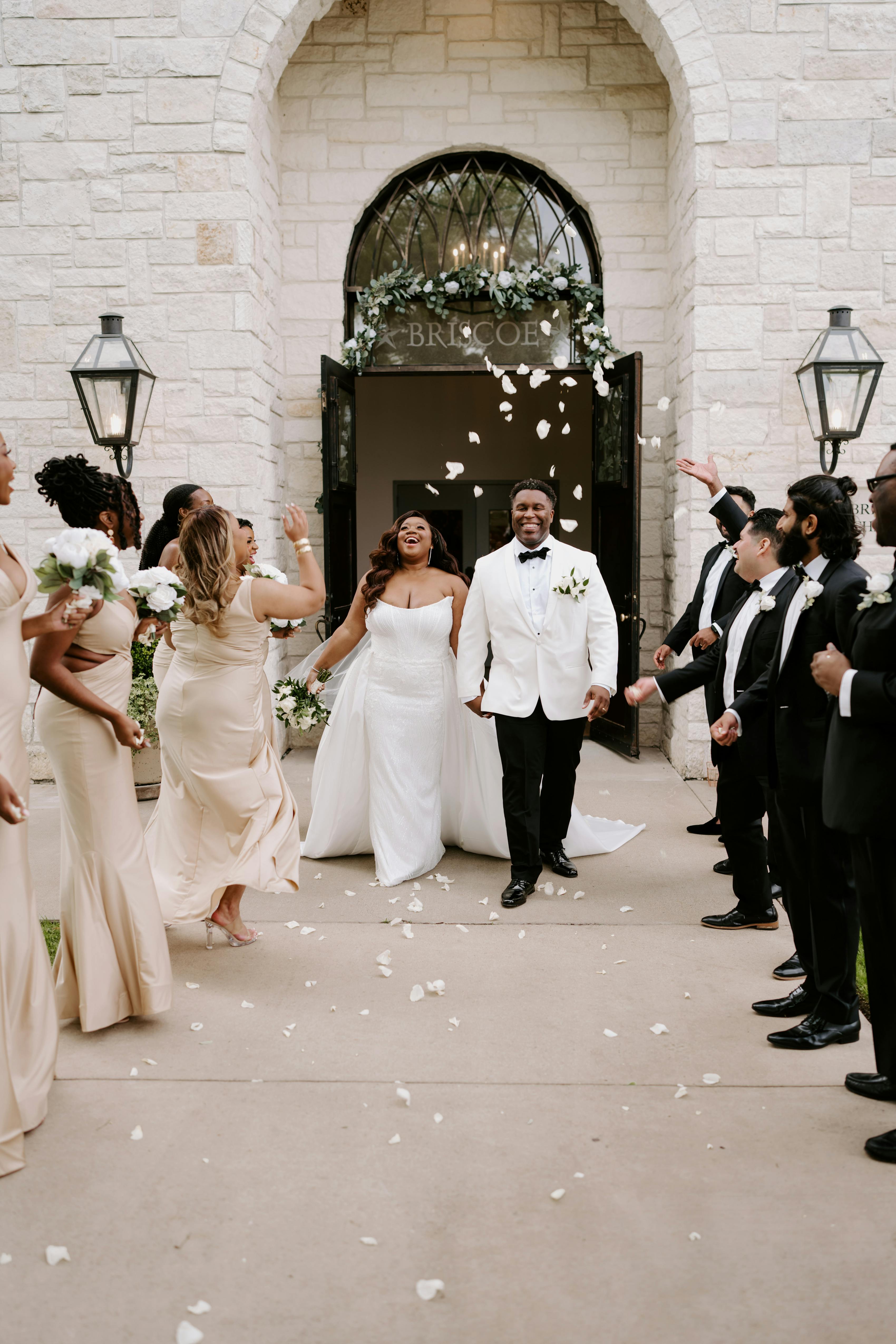 White theme wedding party wearing black groomsman suits and champagne bridesmaid dresses