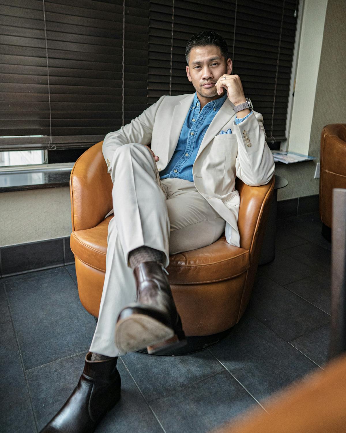 Business casual men's outfit in a tan suit and brown Chelsea boots with a denim shirt