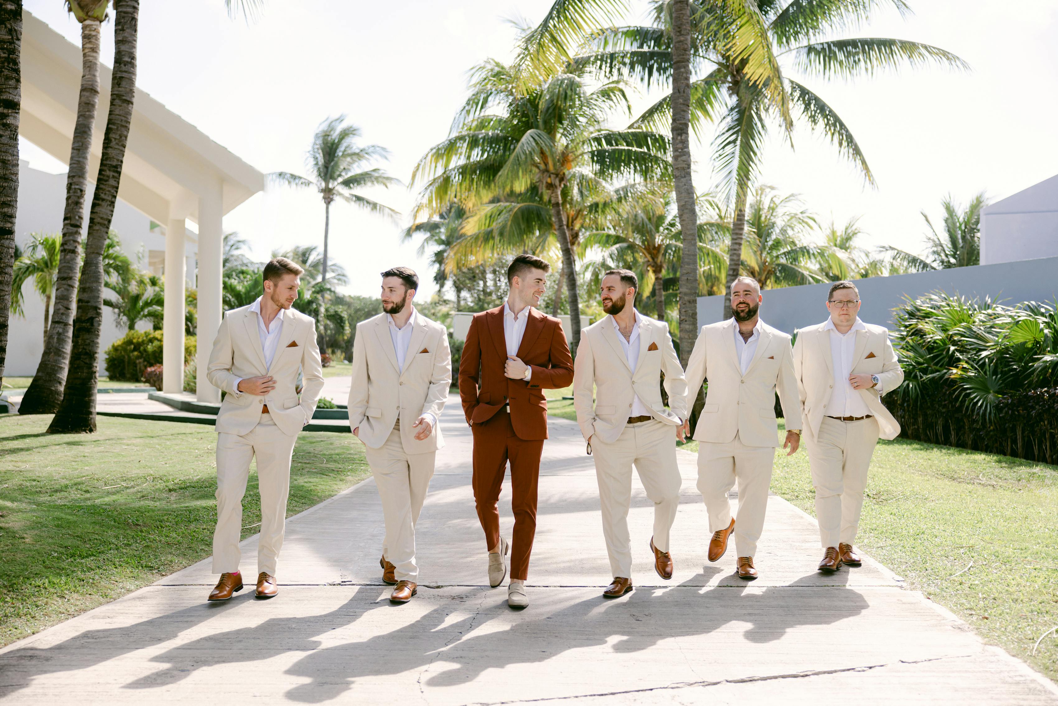 Beach wedding groomsmen style with light tan wedding suits and burnt orange groom's suit