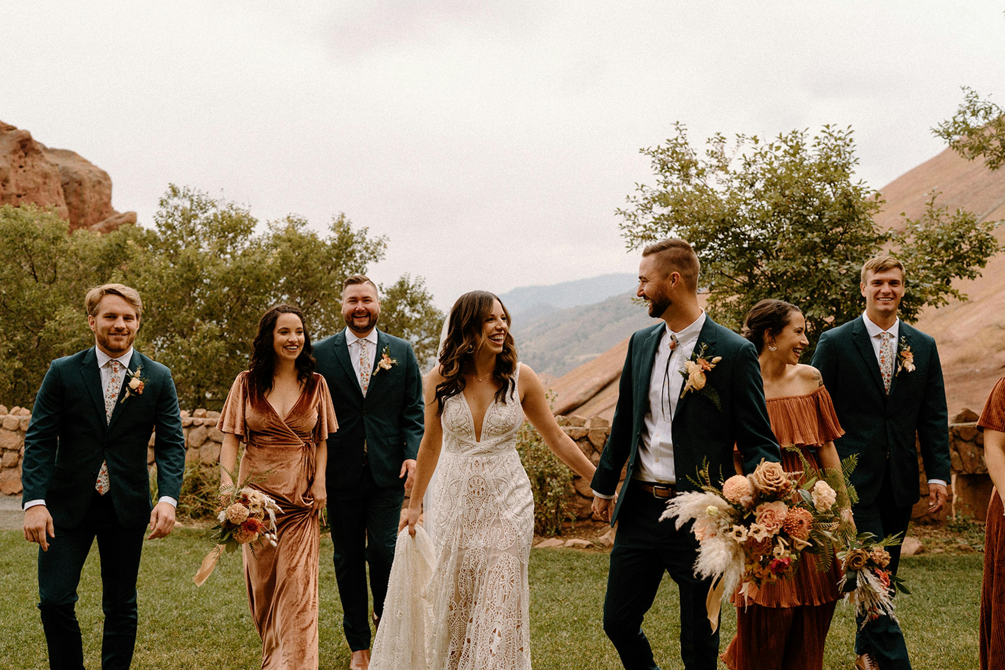 Western bridal party attire with green suits for groomsmen and terra cotta dresses for outdoor wedding