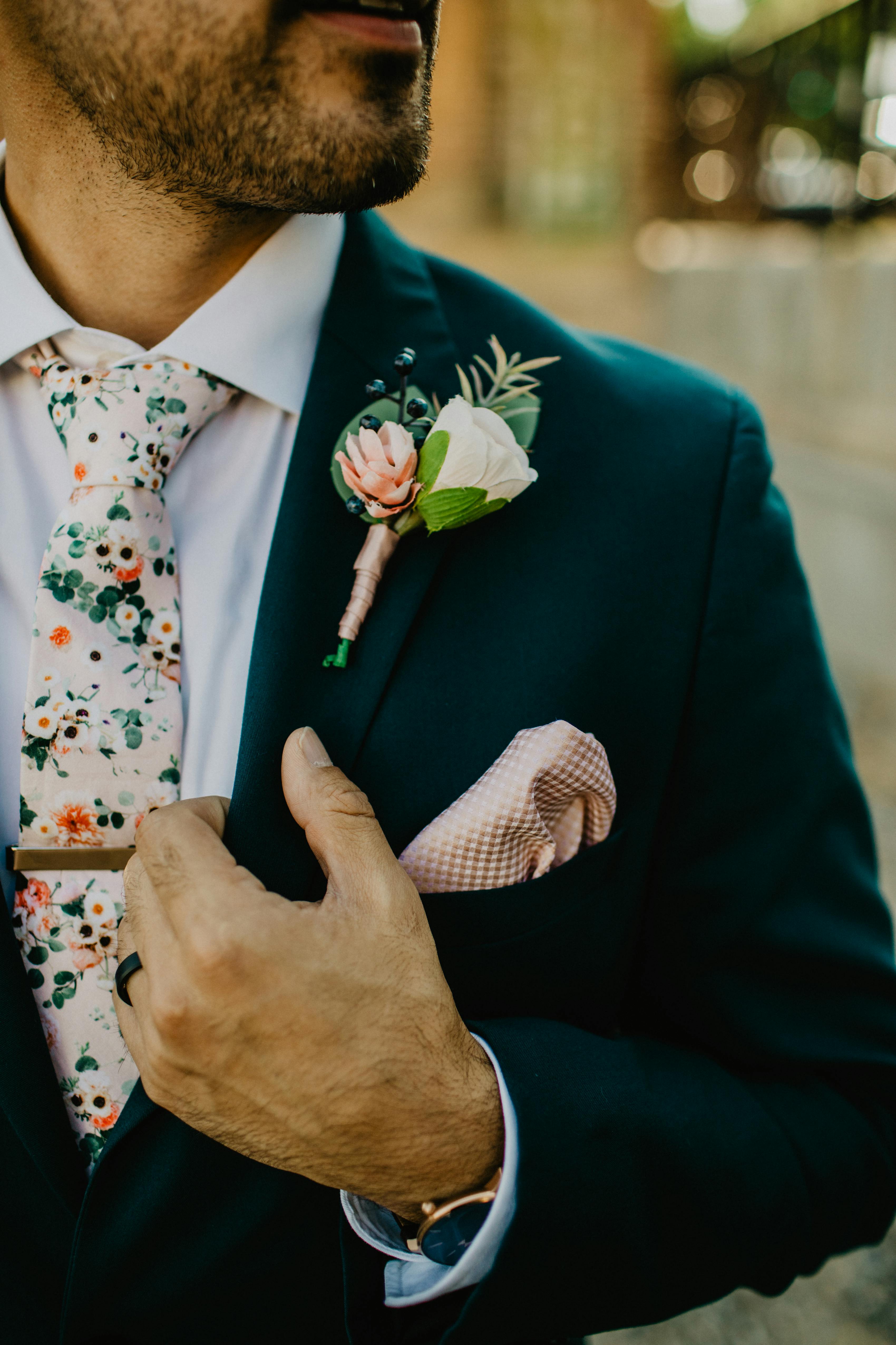 Groom's wedding suit in dark teal with floral tie and colorful boutonnière
