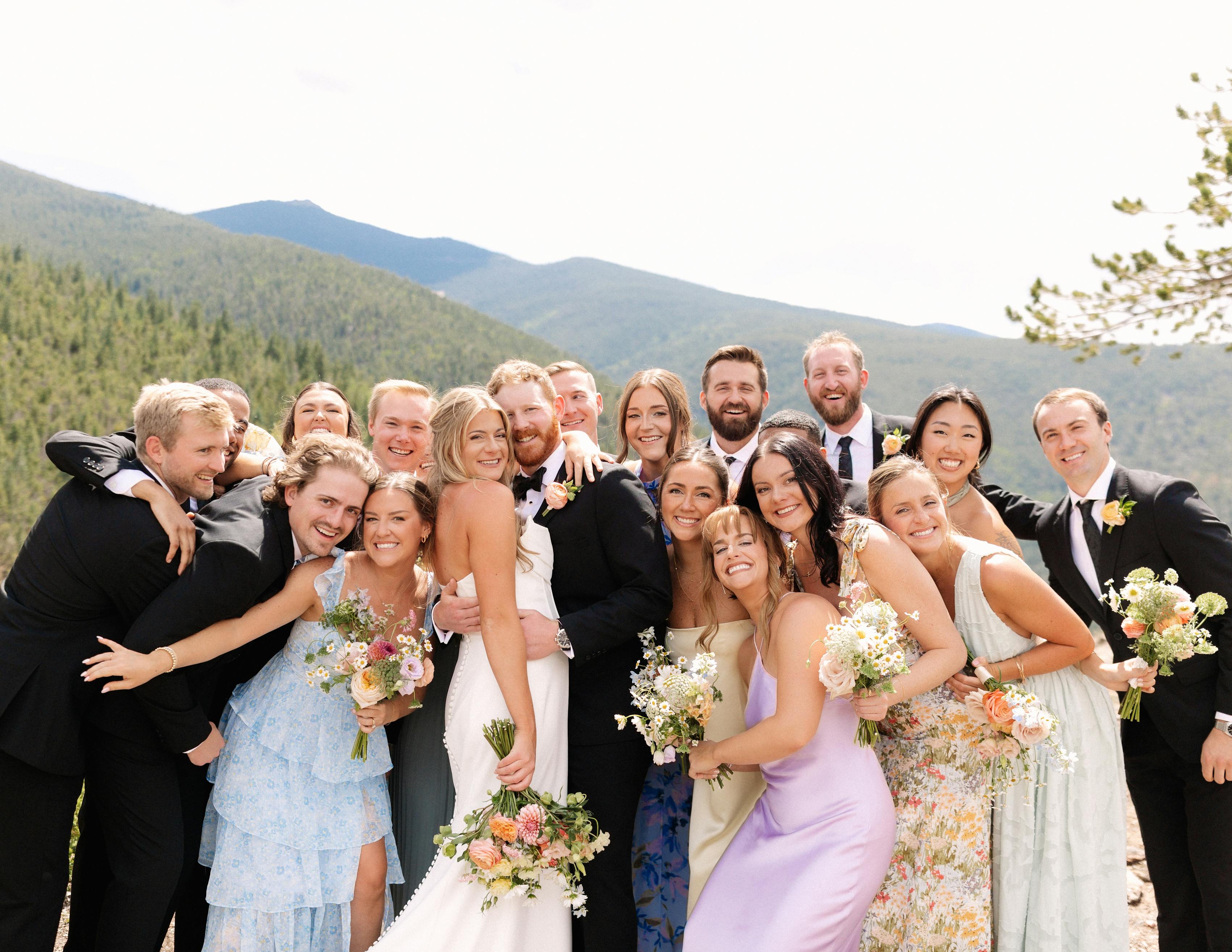 Pastel bridal party attire with floral bridesmaid dresses and black tuxedos