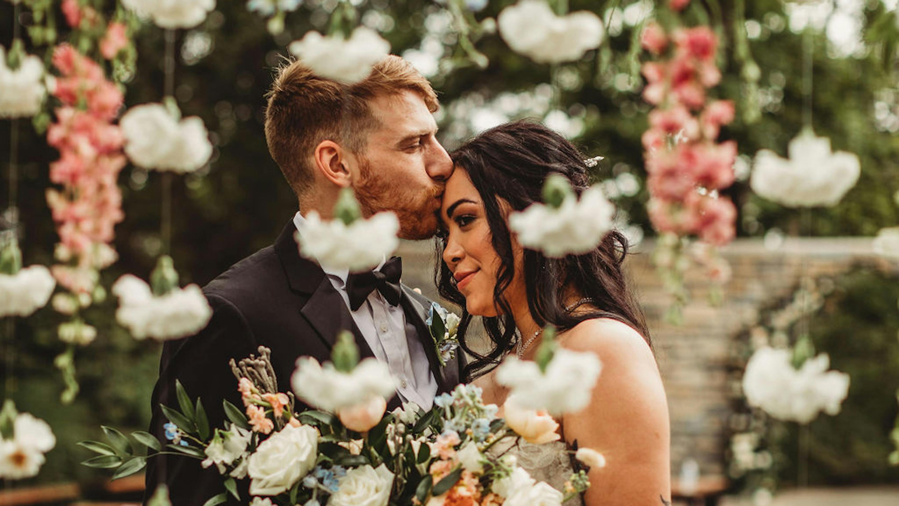 Bride and groom under floral arch for black tie wildflower wedding theme