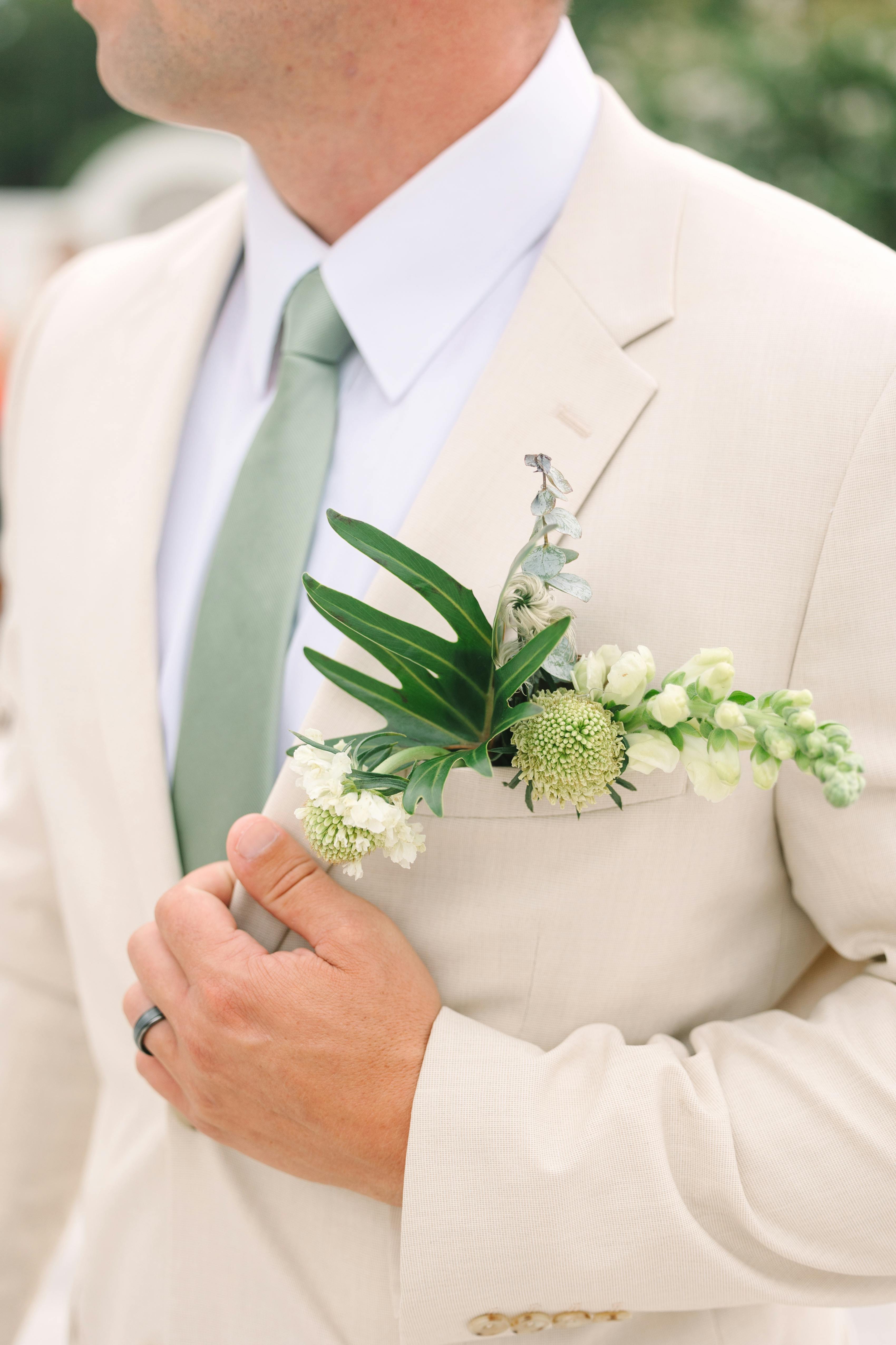 Light tan men's suit with sage green tie for summer wedding attire