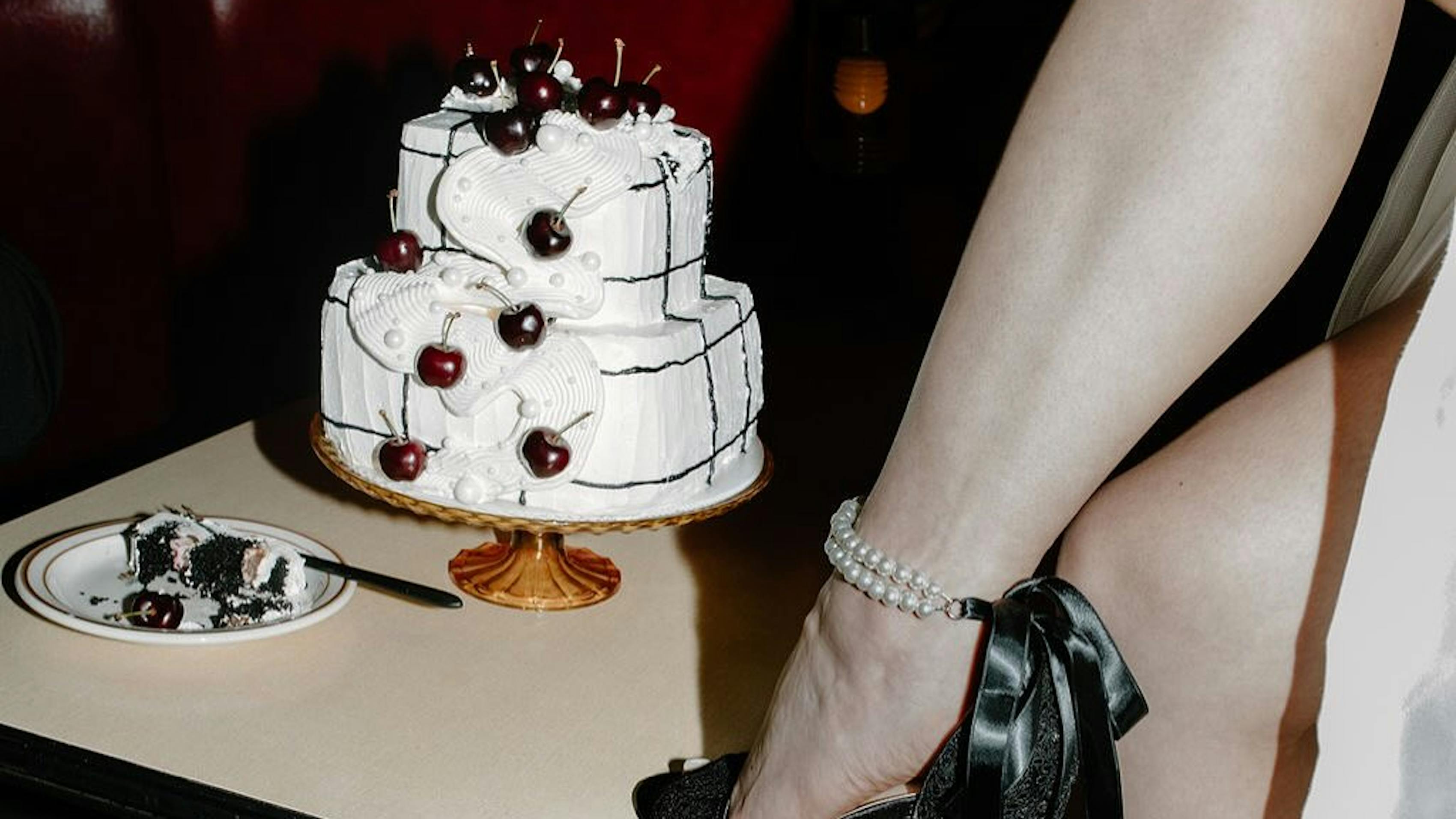 Dark romance wedding theme with cherry wedding cake and black ribbon bridal heels