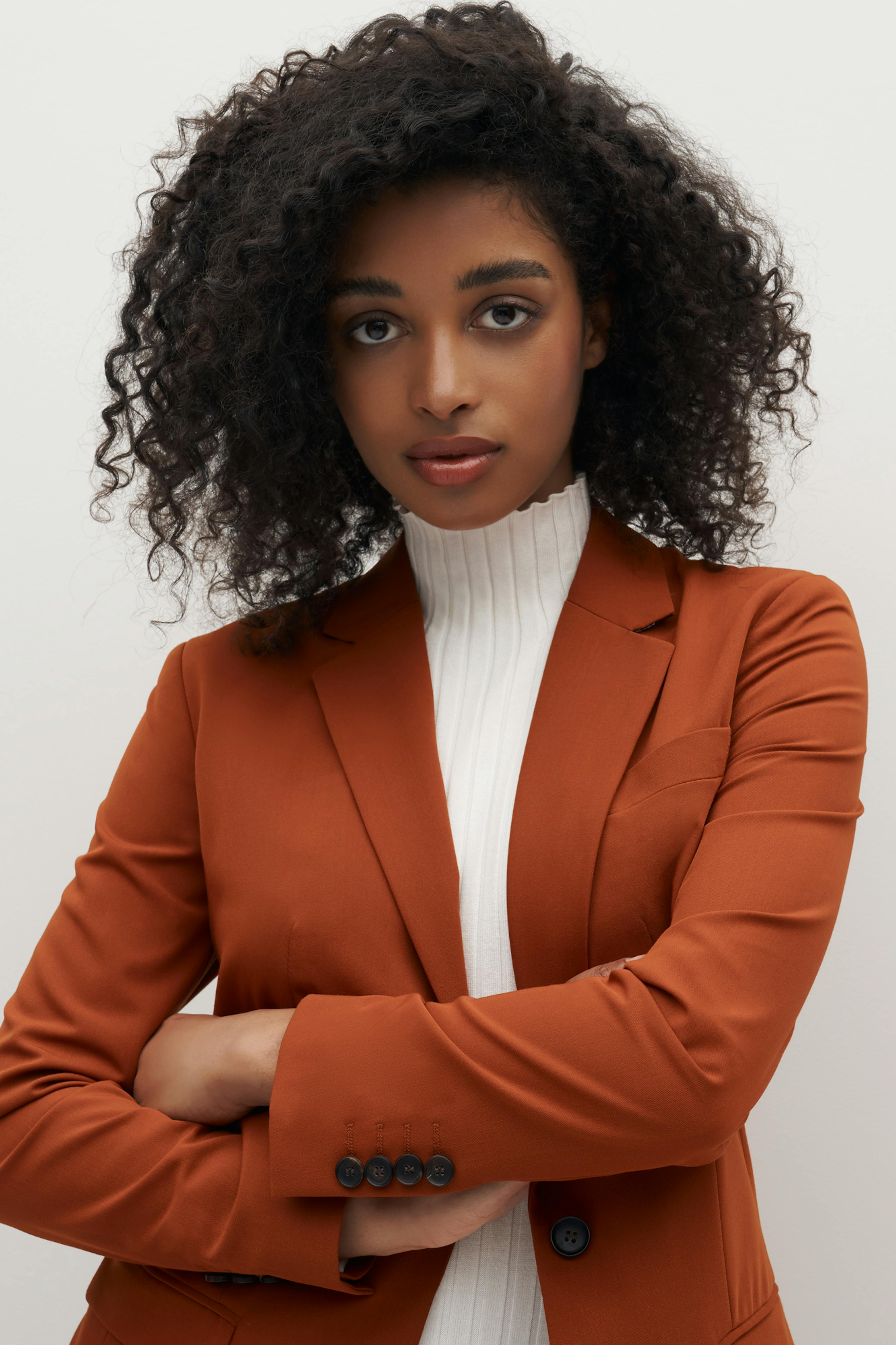 Women's suit outfit in burnt orange blazer with cream white turtleneck