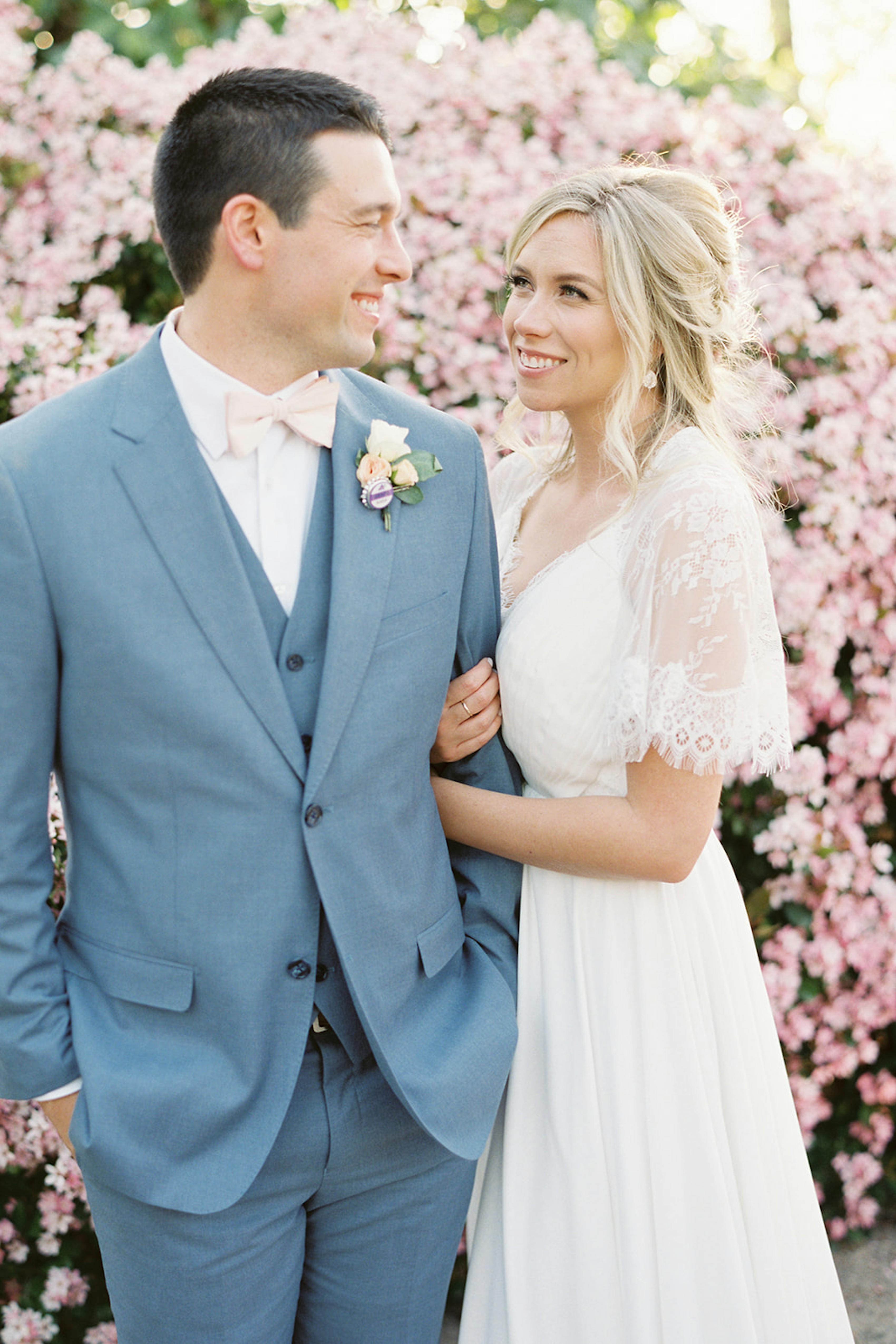 Light blue groom suit with vest and blush pink bow tie and lace wedding dress