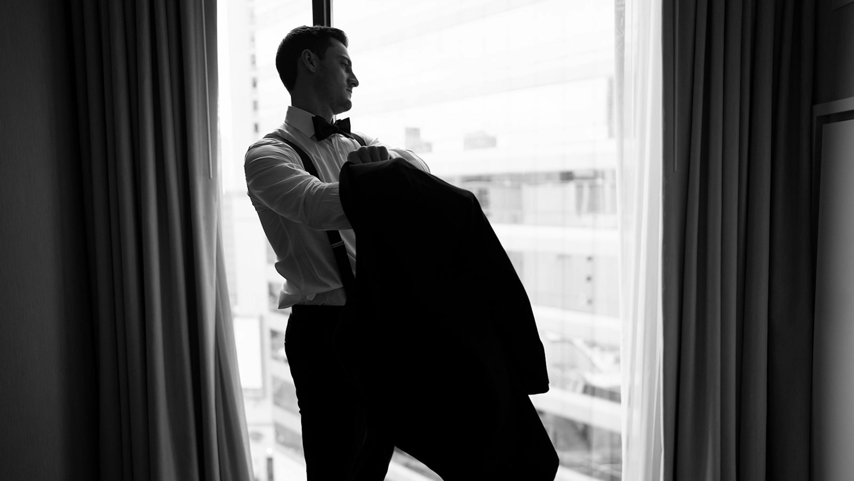 Groom preparing for wedding day getting dressed in tuxedo