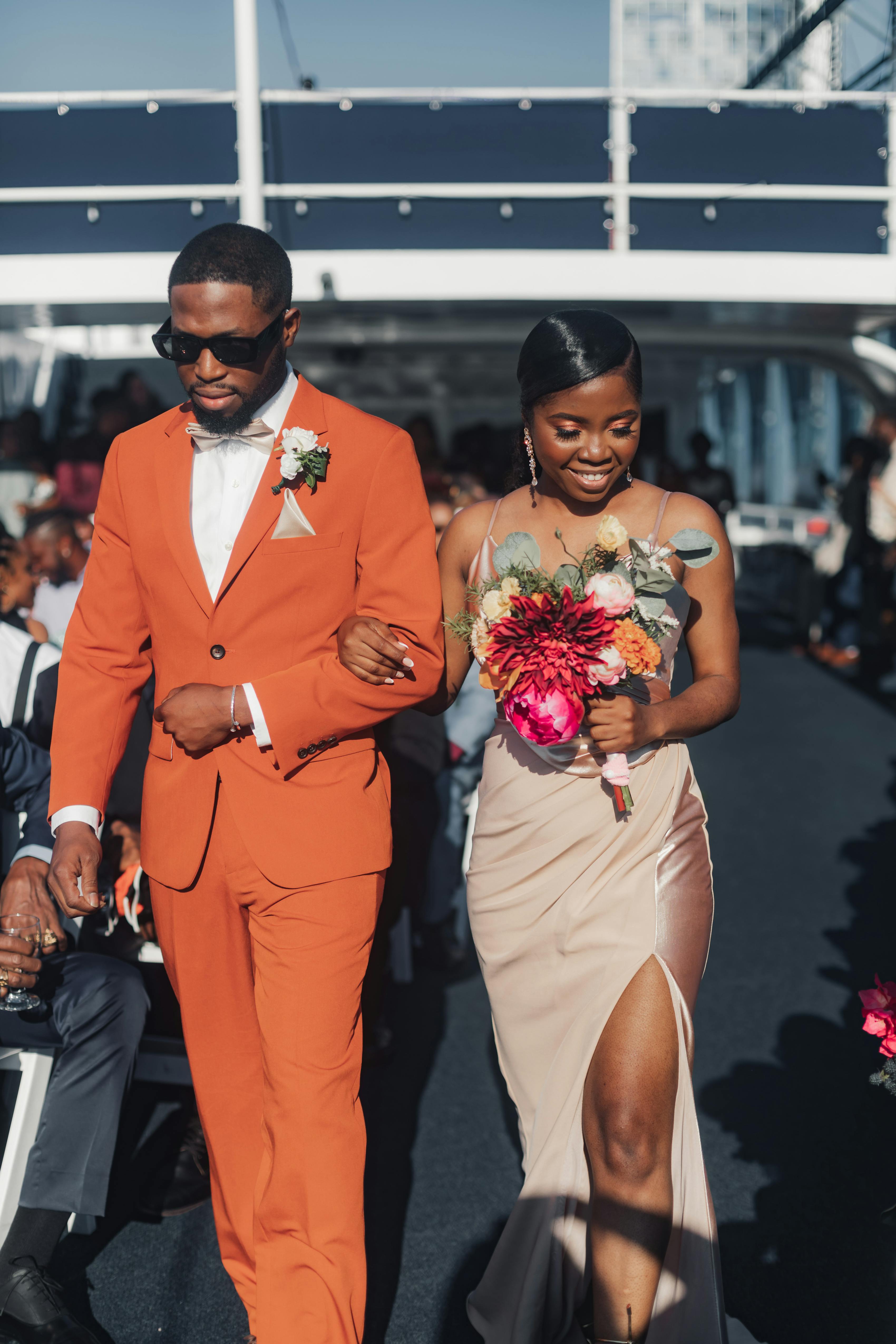 Burnt orange groomsman suit with champagne bridesmaid dress and bright pink flowers