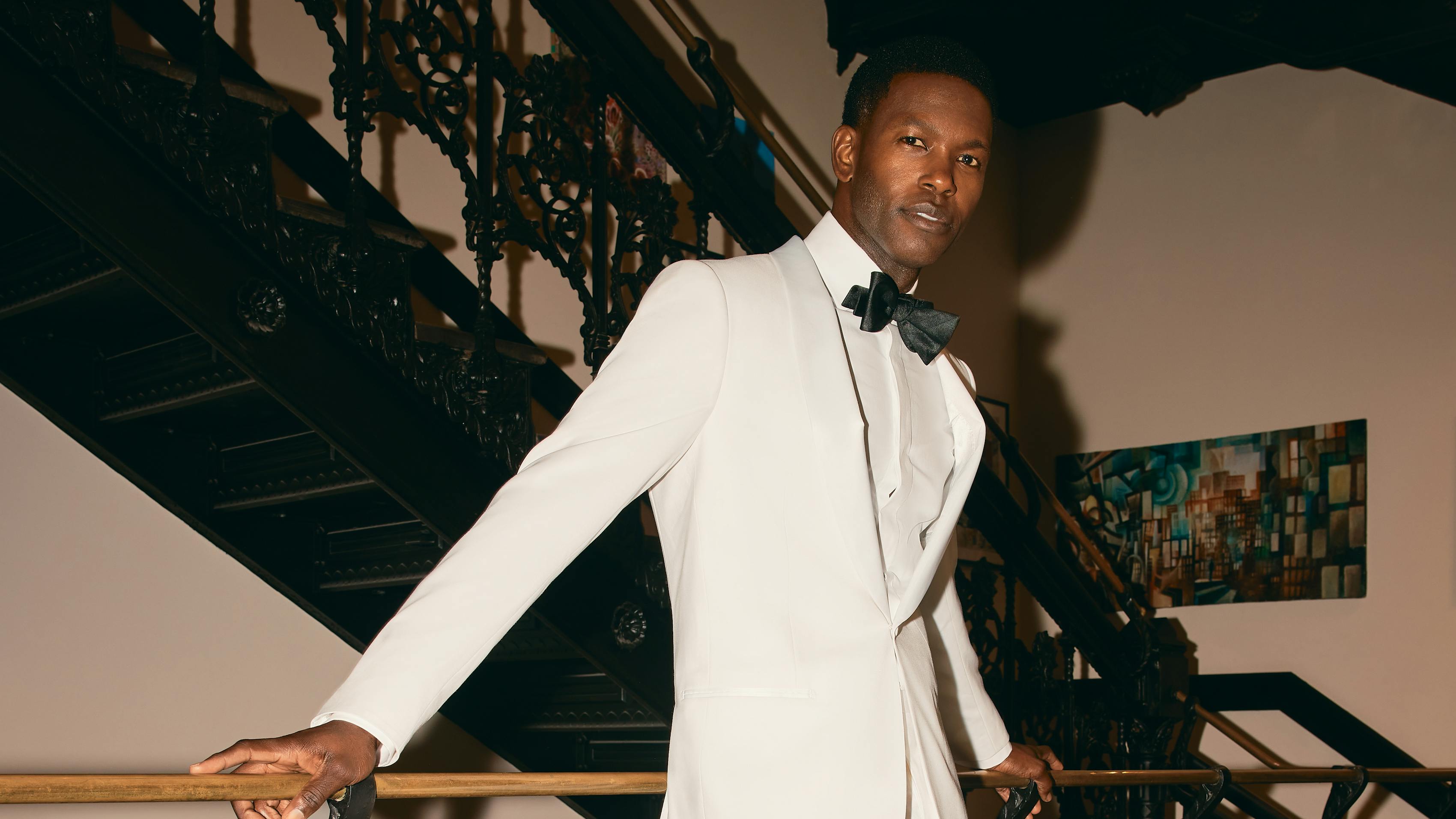 Groom wearing all white tuxedo in fancy hotel wedding venue