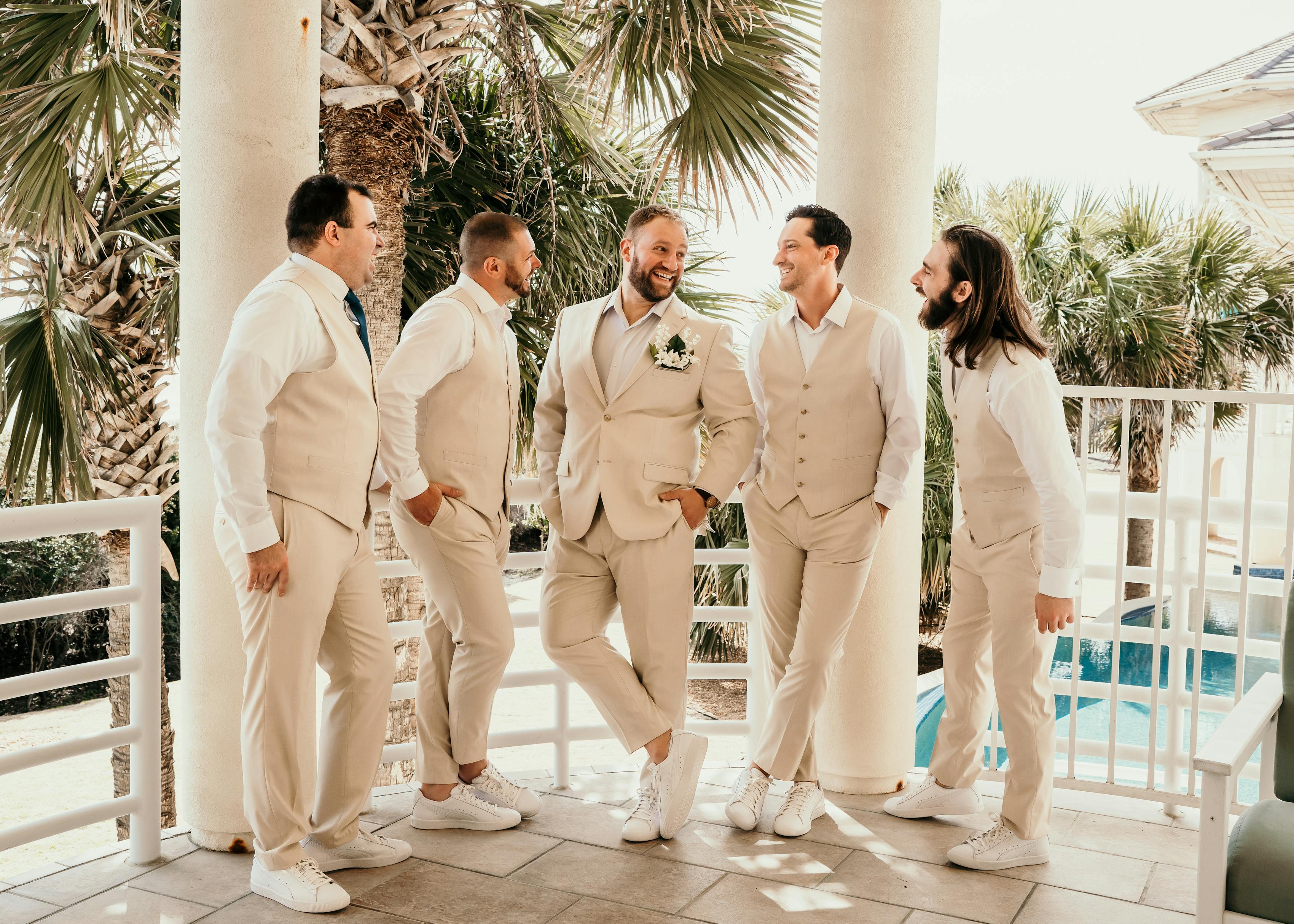 group of groomsmen in tan wedding suits poolside at a destination wedding