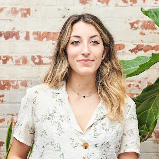 Annmarie Ciacciarelli stylist headshot in short sleeve button up shirt in front of brick backdrop.