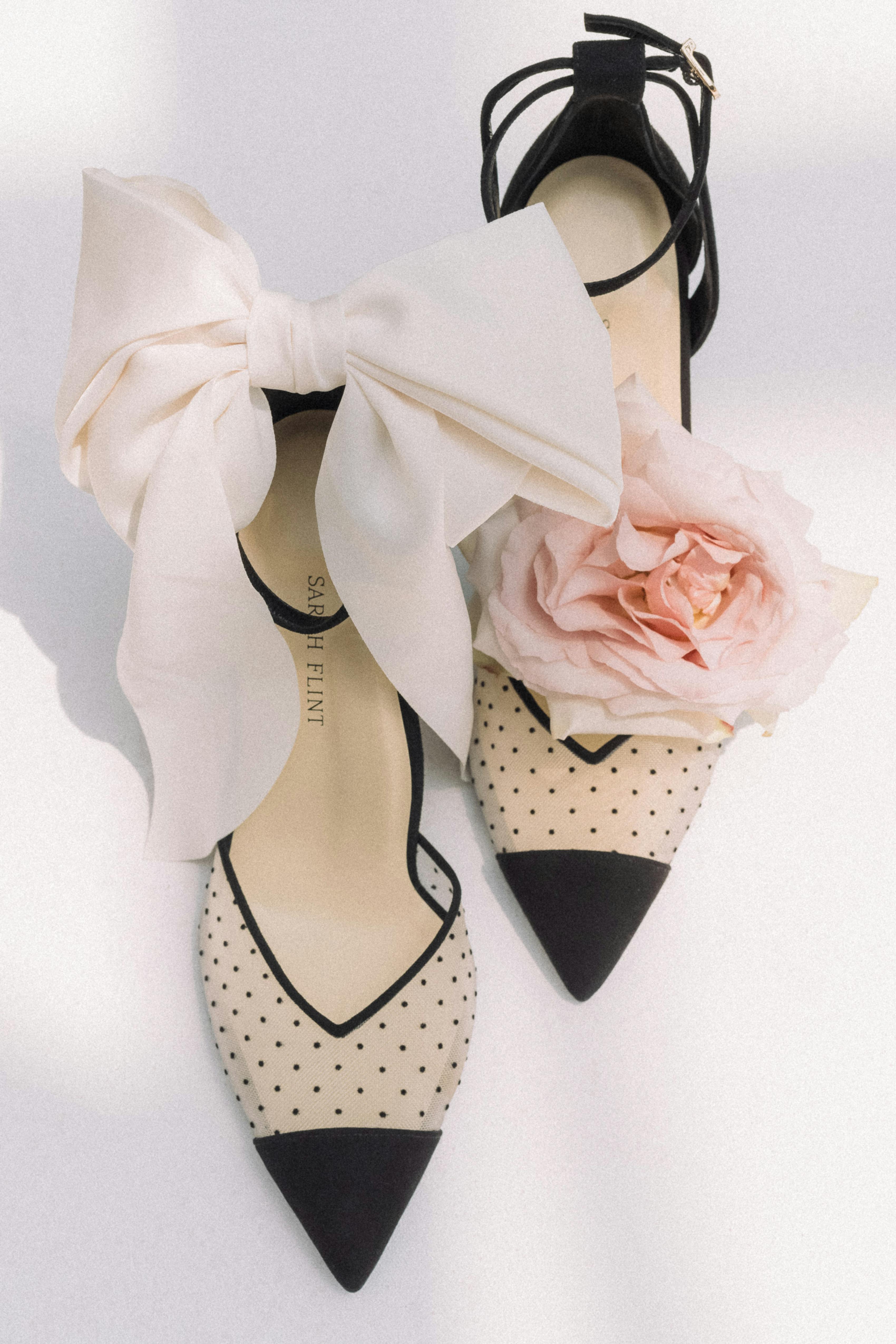Cocktail outfit accessories for women with Swiss dot black cocktail heels and a light pink hair bow.