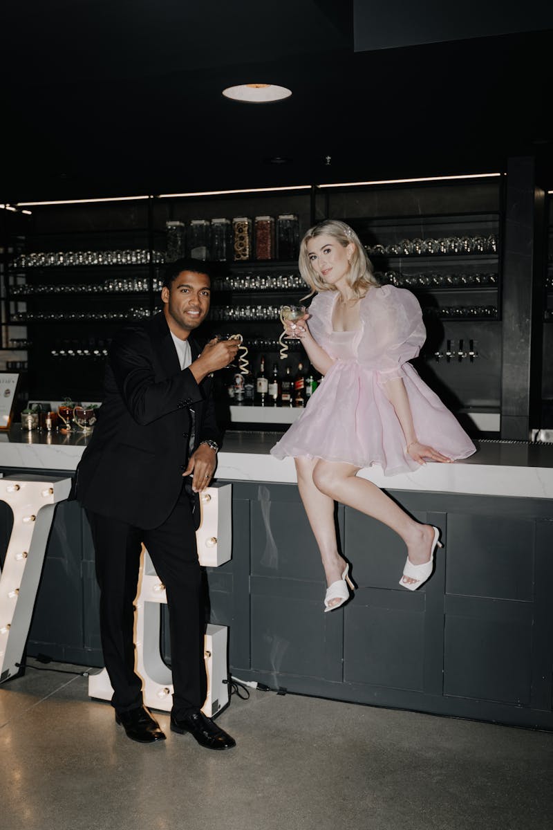 Man and woman at fancy event with cocktail dress code wearing black suit with t-shirt and puff sleeve organza pink dress