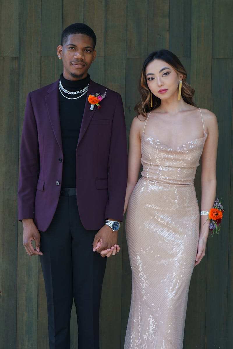 Man in burgundy suit jacket matched with black suit pants and his date in champagne sequin dress