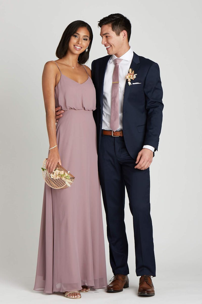 Couple attending wedding in appropriate cocktail outfits for men and women with a mauve dress and navy suit