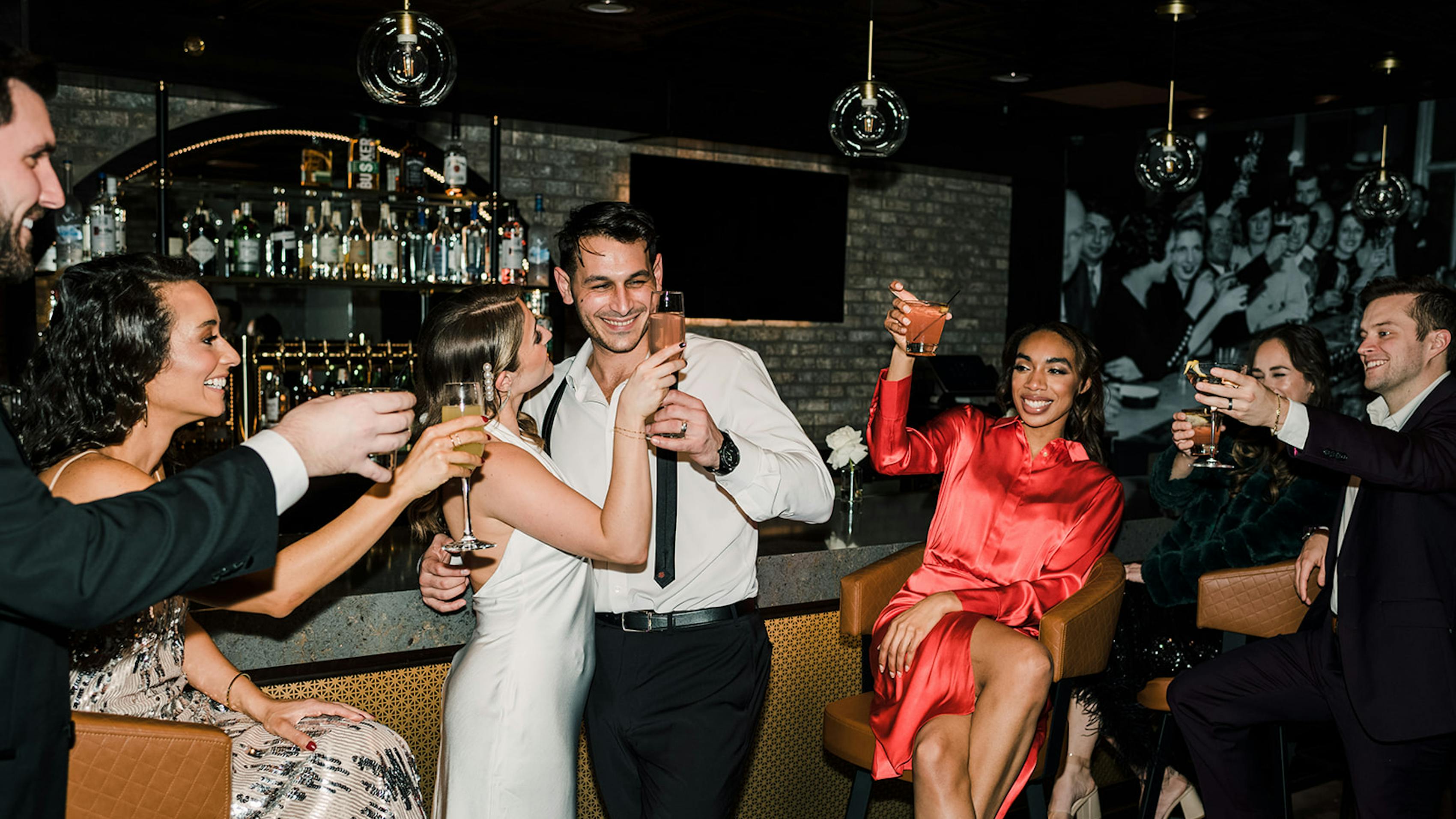 Cheers at cocktail wedding afterparty with guest outfits of men's suits and special event dresses for women