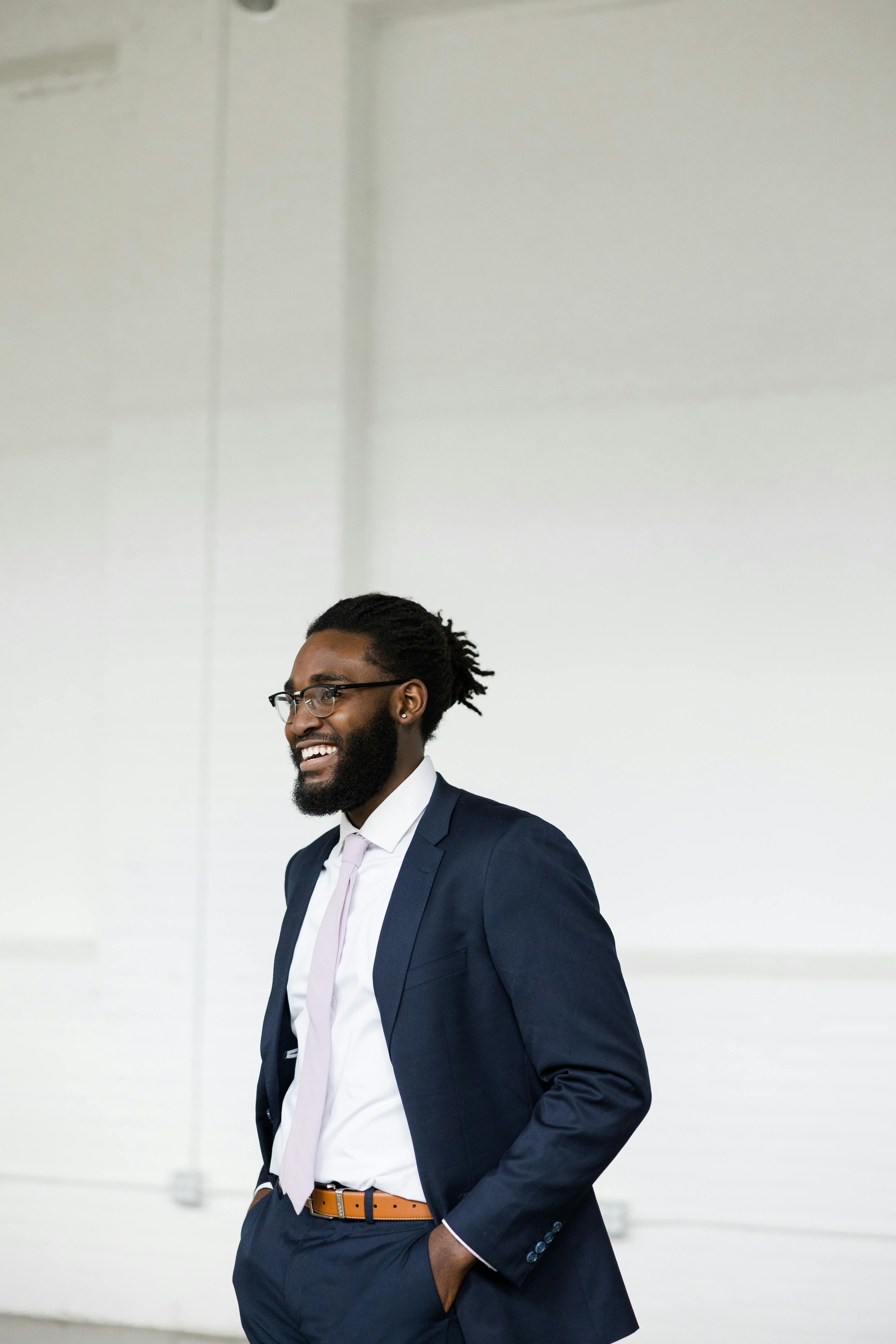 Polished men's event style with a navy blue suit, lavender tie, and brown belt.