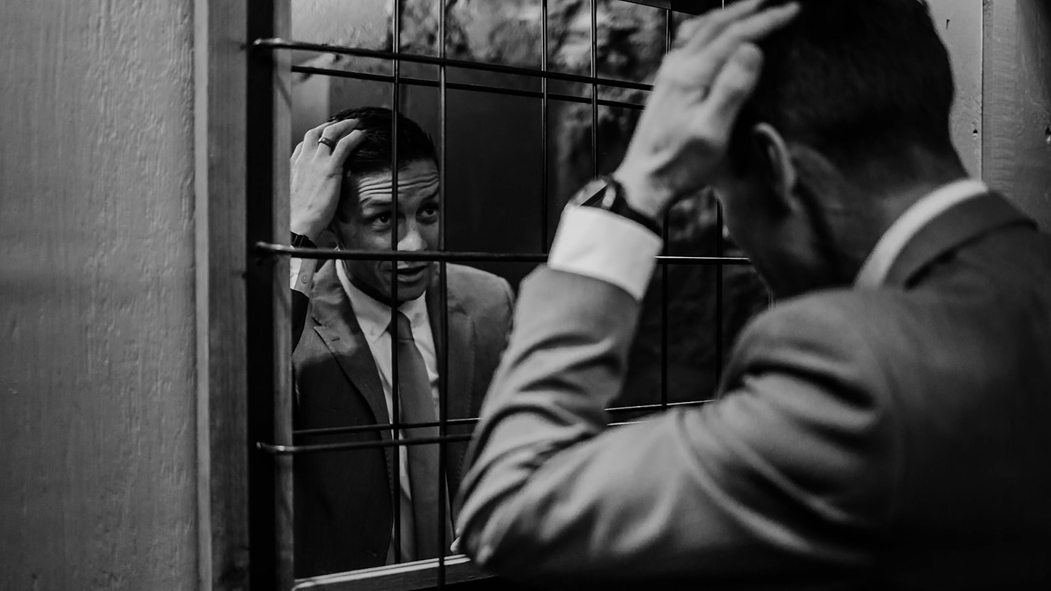 Man looking at his cocktail attire suit and tie outfit in the mirror