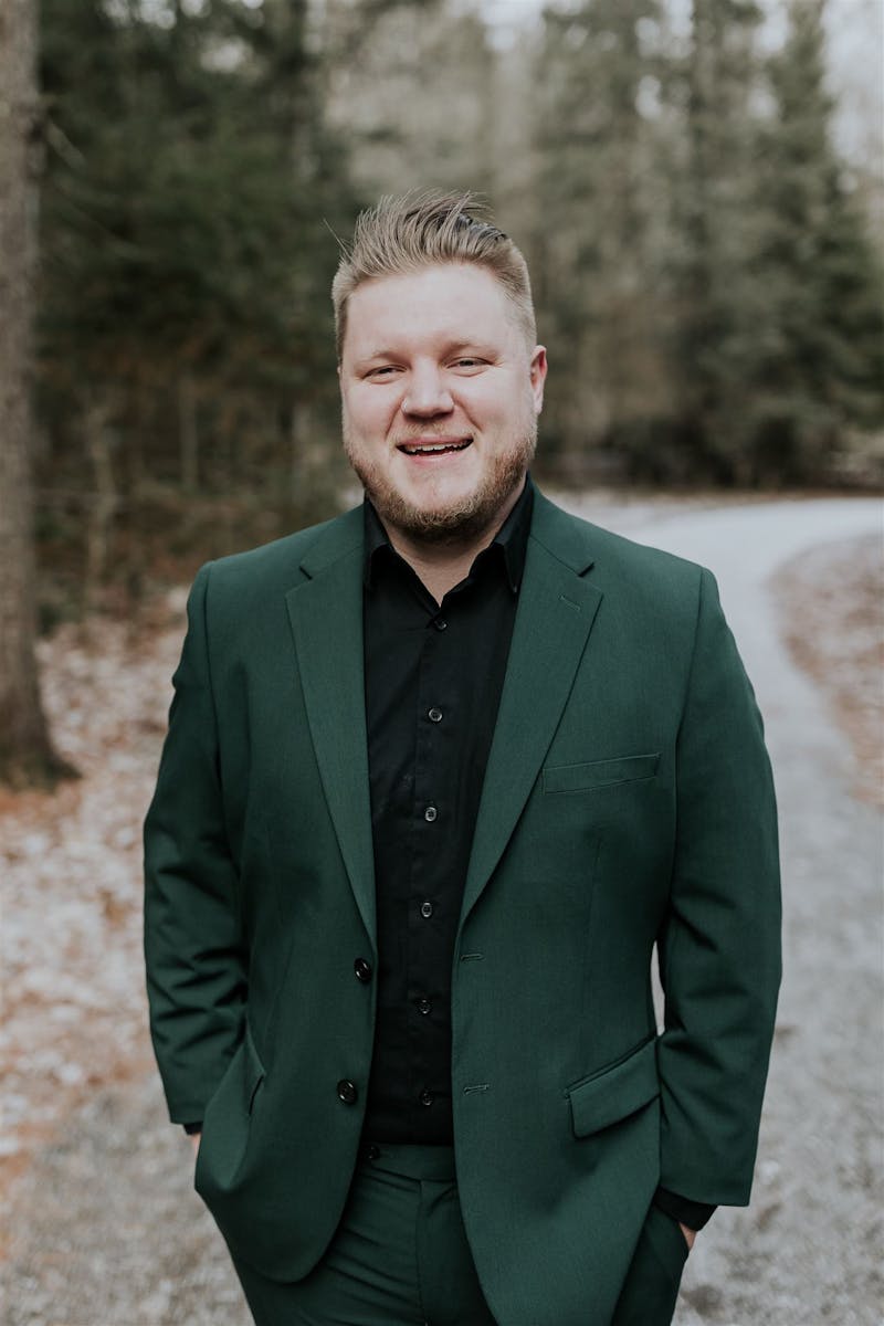 Men's dark forest green suit with black dress shirt for an outdoor cocktail event