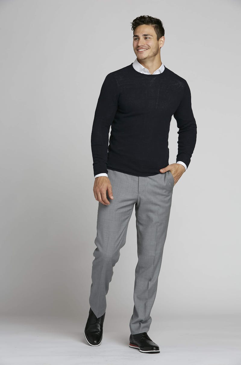 Professional men's outfit with sweater, button-up shirt, and light grey slacks.