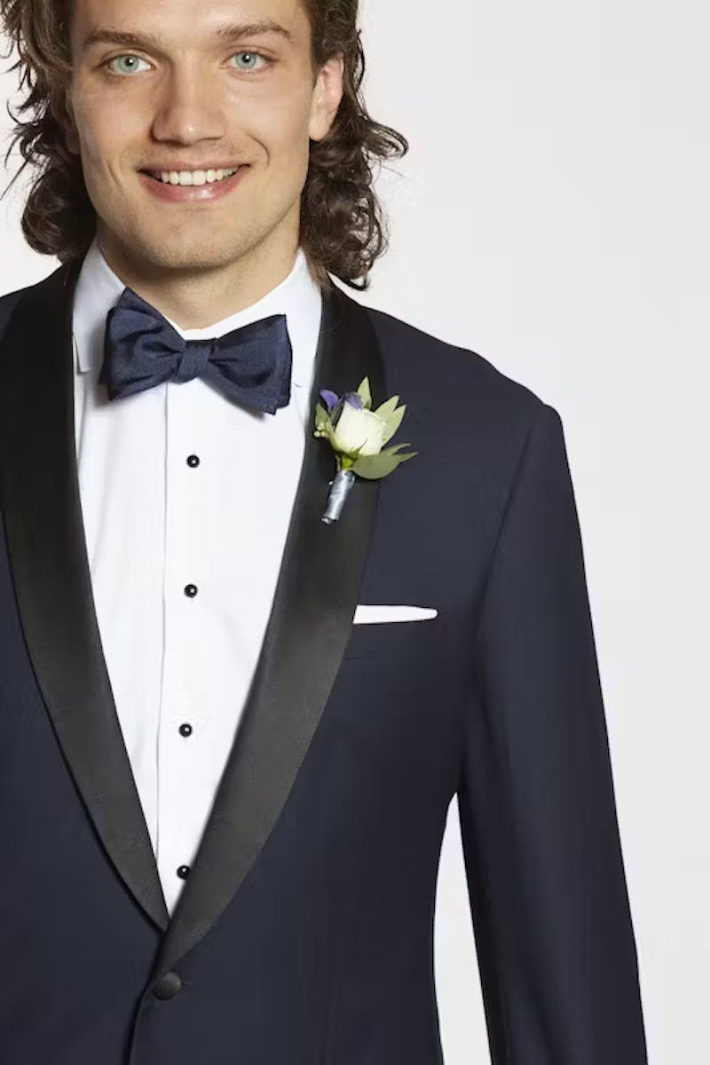 Man dressed for black tie event showing how to pin a boutonniere on a shawl lapel tuxedo