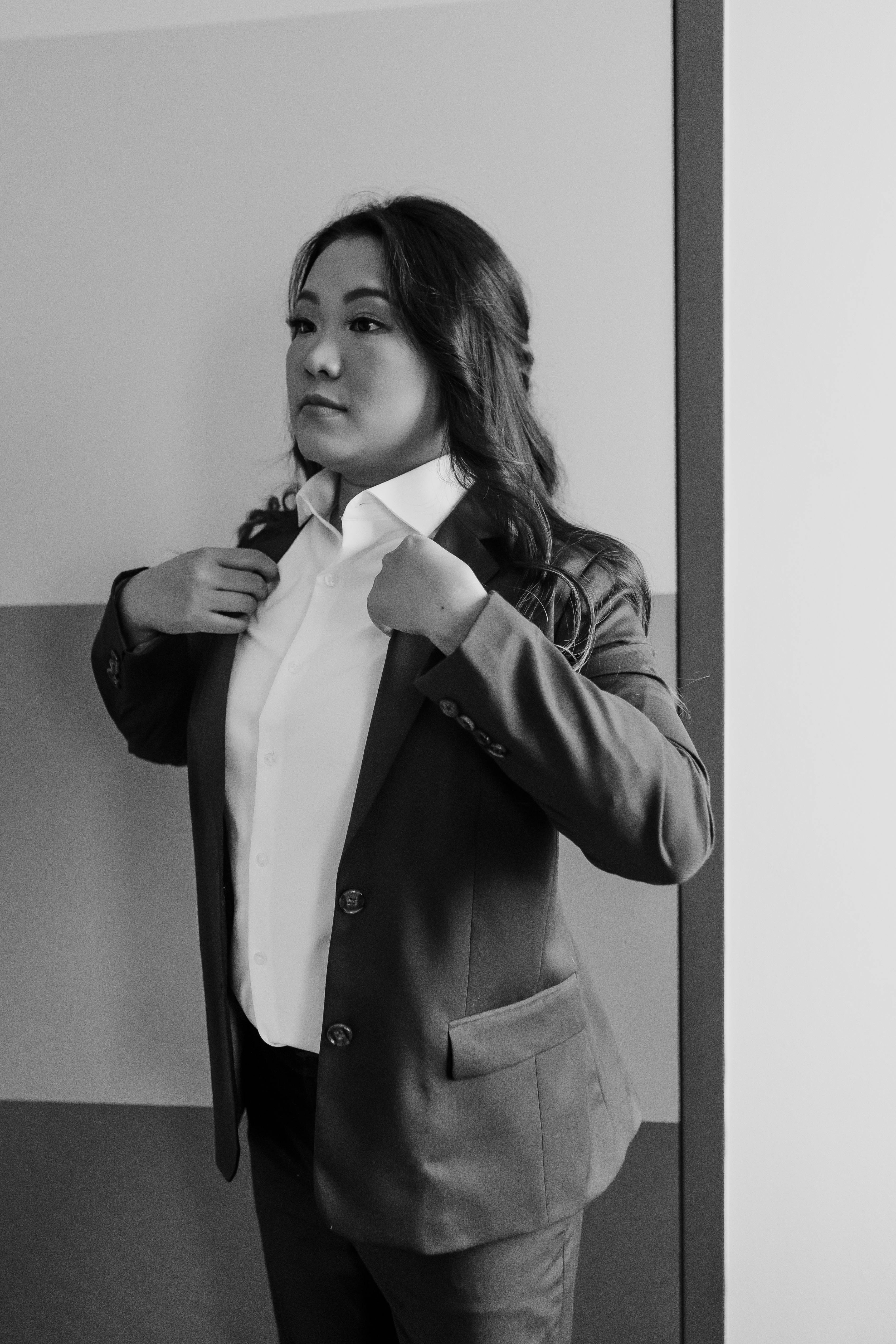 Dressed for work in women's business professional office outfit of pantsuit and white button down dress shirt.