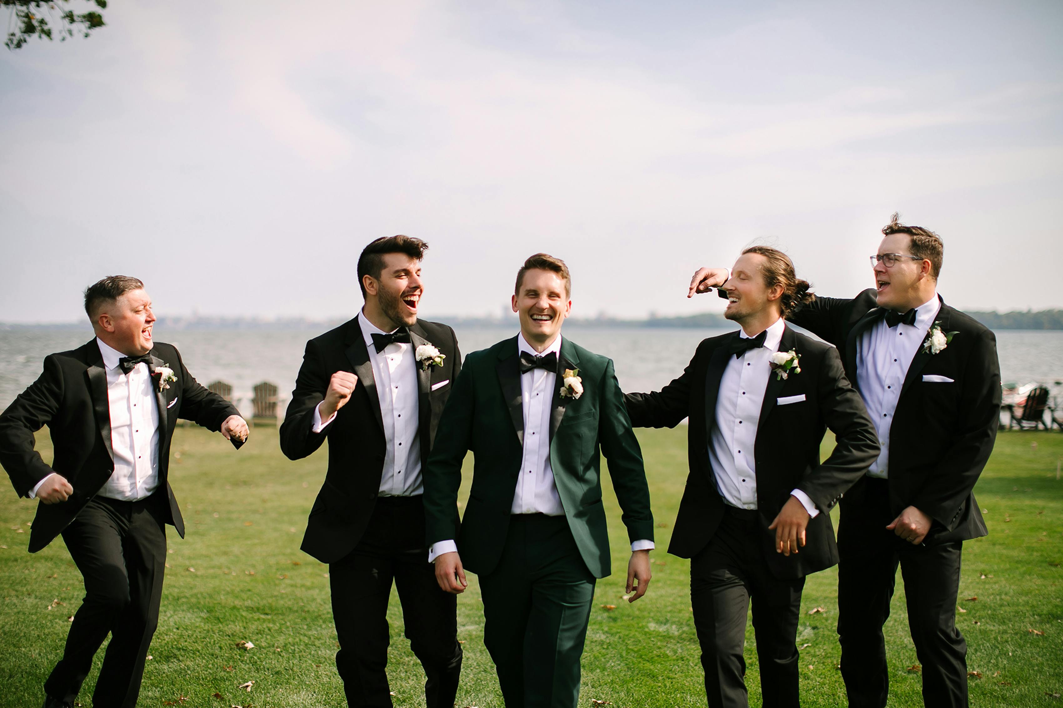 A group of groomsmen before the wedding ceremony the groom chose a dark green tuxedo to stand out among the classic black notch lapel tuxedos of the rest of the group.
