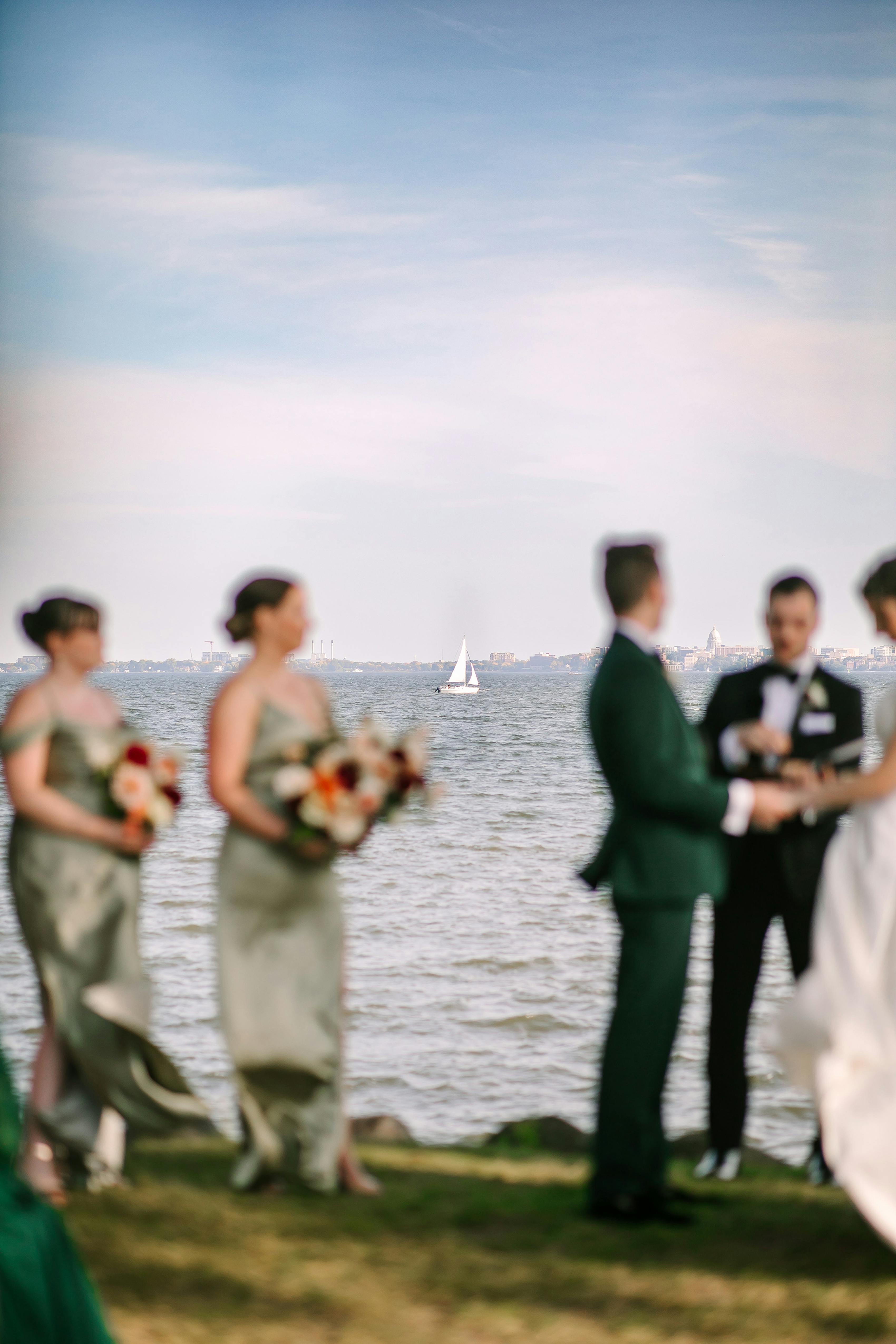 Breezy lakeside wedding ceremony in Wisconsin with green wedding party attire.