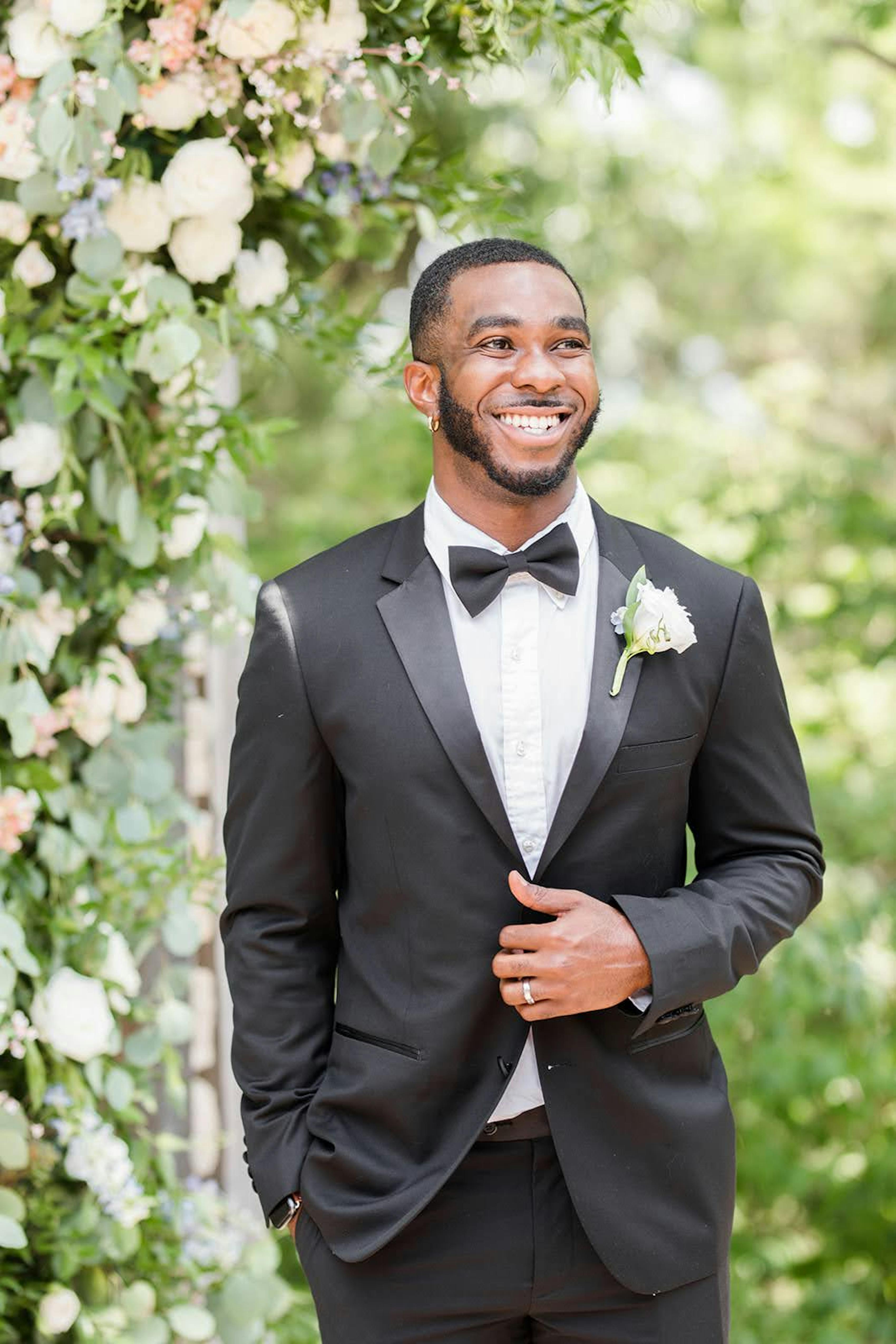 Groom wearing a formal black bow tie with a black tuxedo at outdoor wedding
