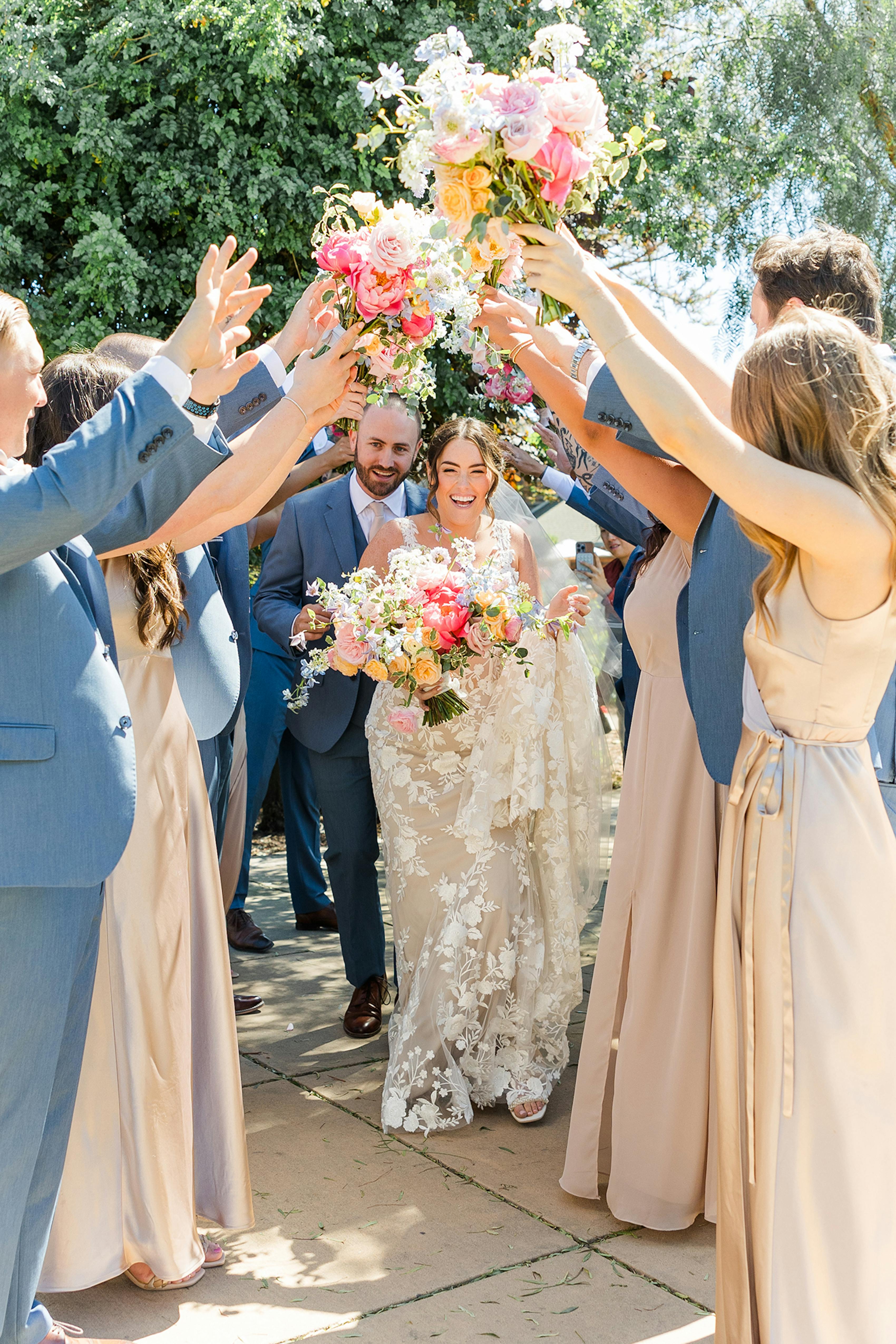Popular wedding party pose where bridal party creaates and archway and bride and groom run underneath their arms.