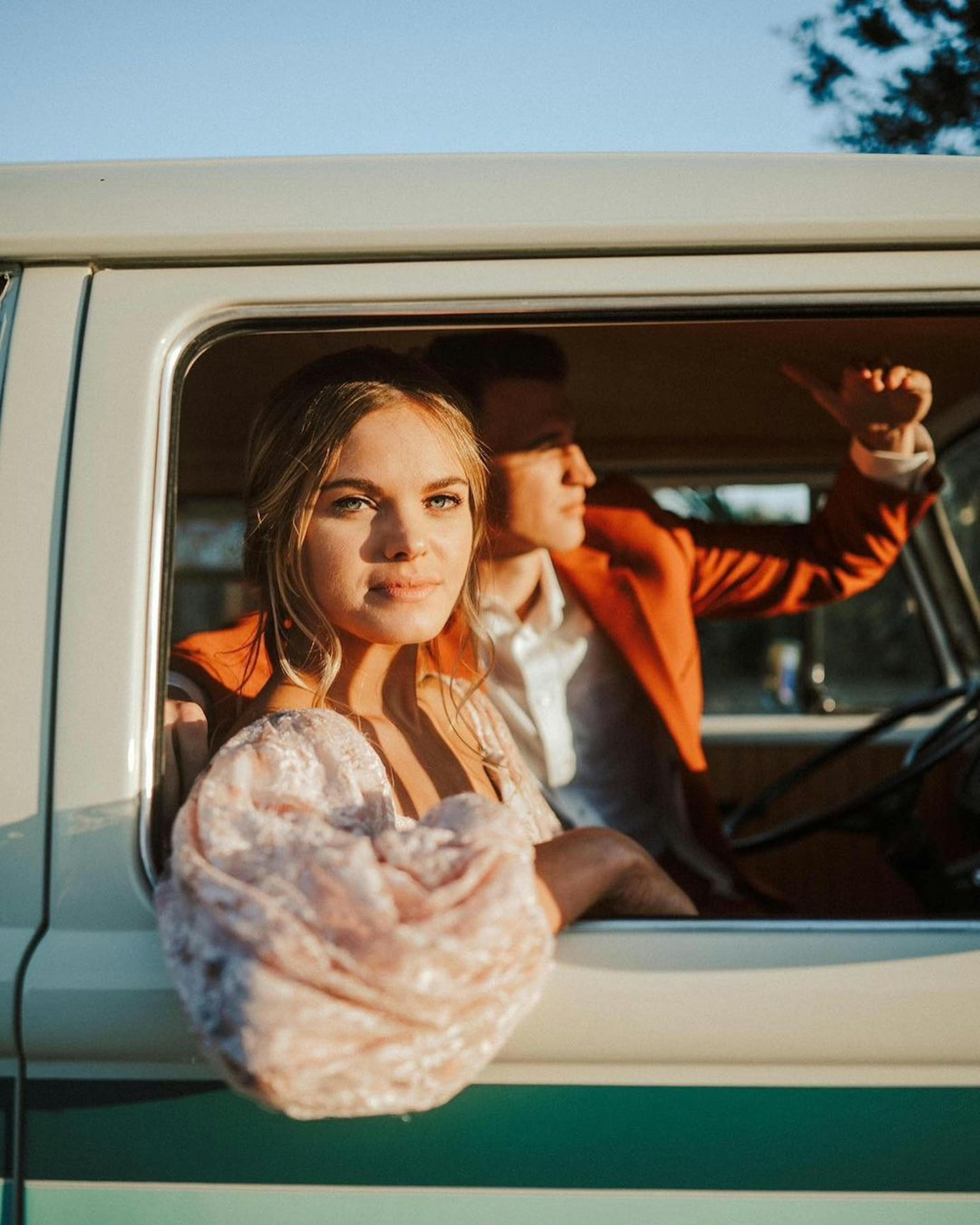 Blush pink and rust orange wedding color combo with boho bride and groom in vintage car
