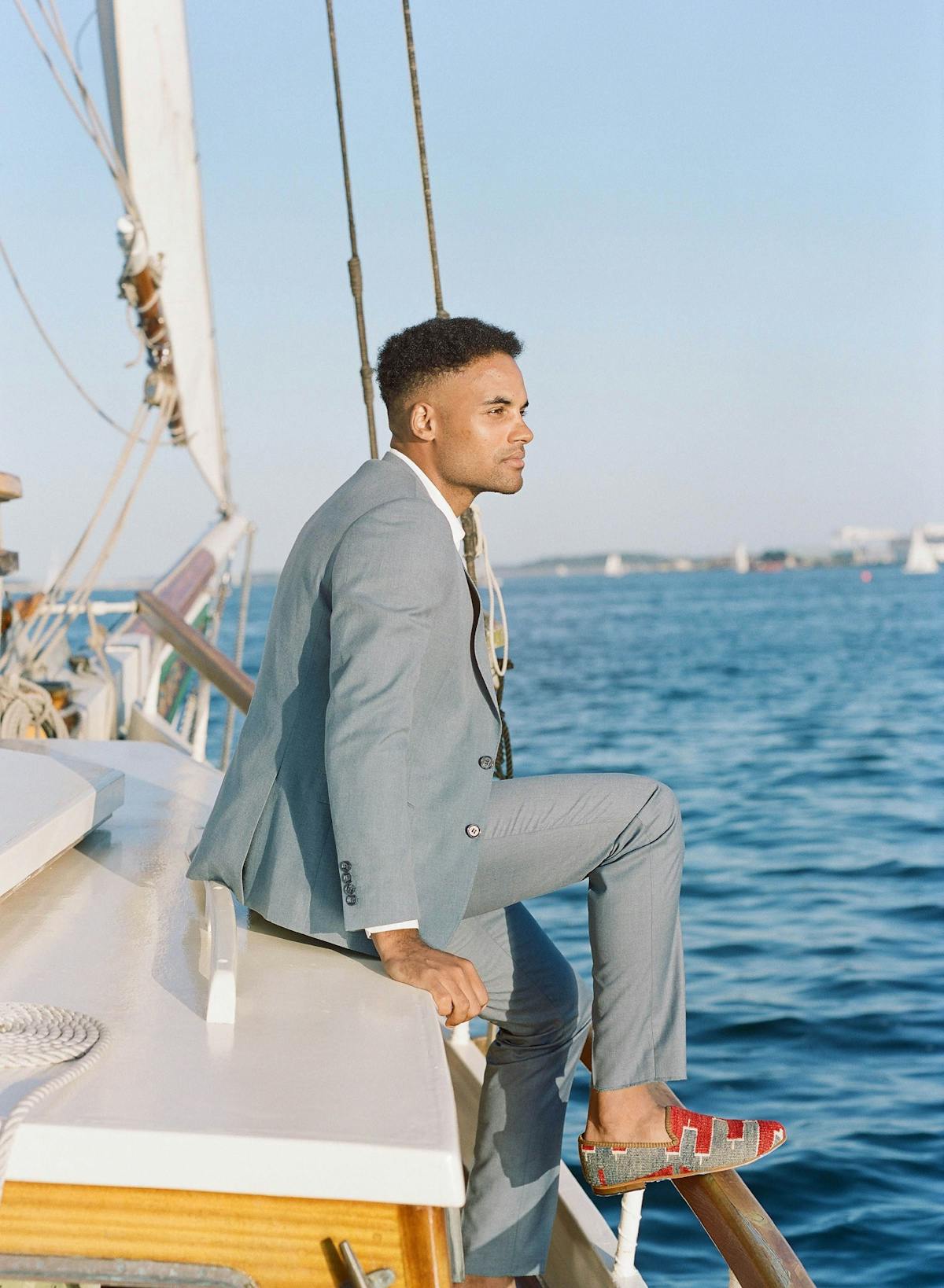 Light blue suit for wedding guest sitting on a boat wearing loafers