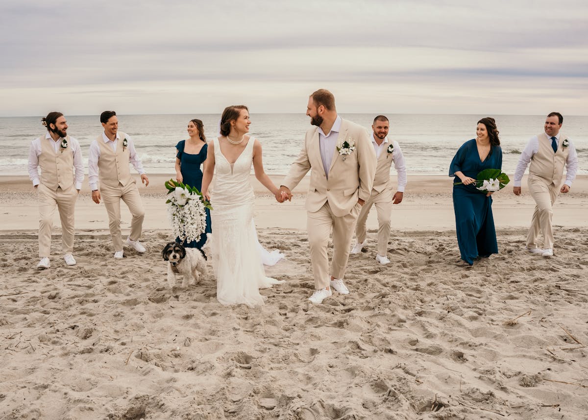 Wedding party portrait with tan groomsmen suits and blue bridesmaid dresses on the beach