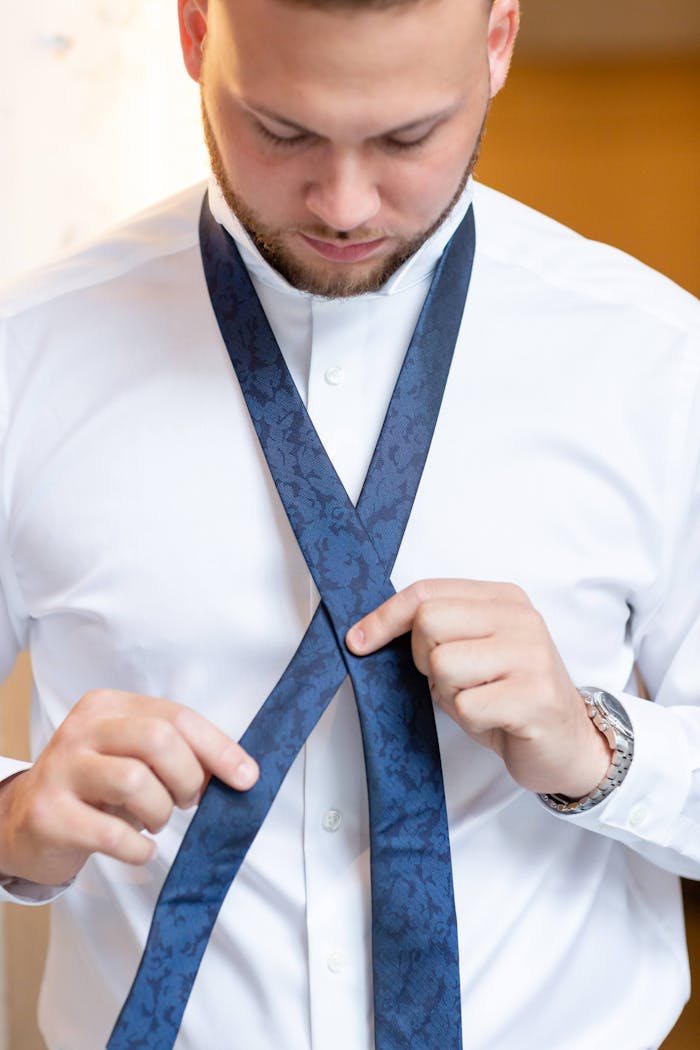 Man working through easy steps to tie a necktie with a blue floral pattern