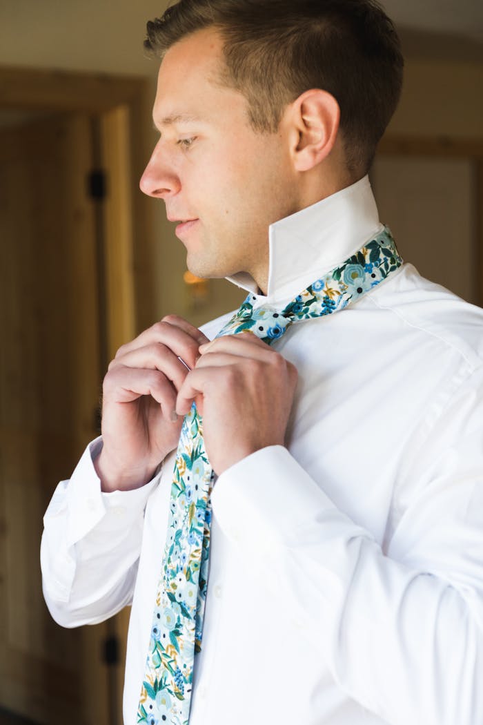 Man tying tie with colorful floral necktie for wedding