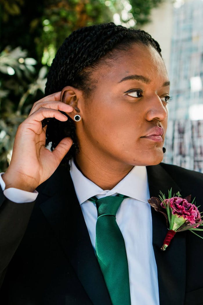 Woman wearing green silk tie and suit for women before adjusting her tie knot