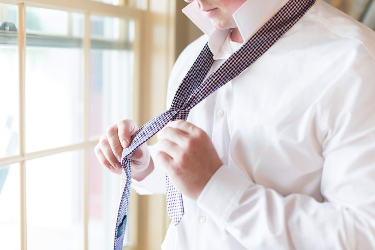 Man learning to tie a tie with a white dress shirt for a formal event