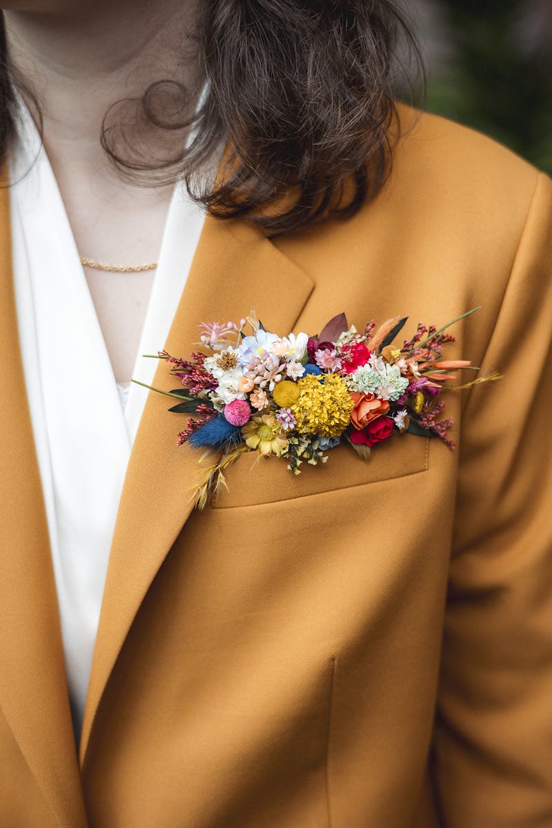 Groomswoman wearing a women's merigold suit, styled with a dried floral pocket boutonniere