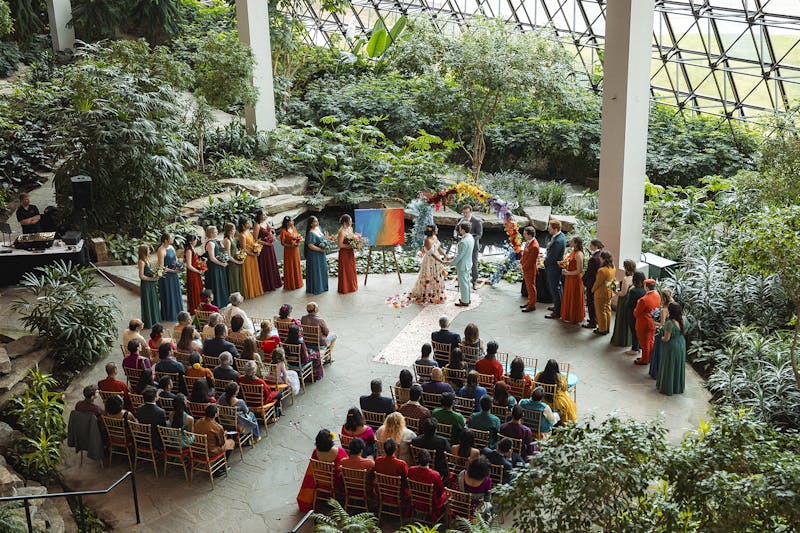 A bird's eye view of a colorful + crafty wedding in a greenhouse-like atrium.