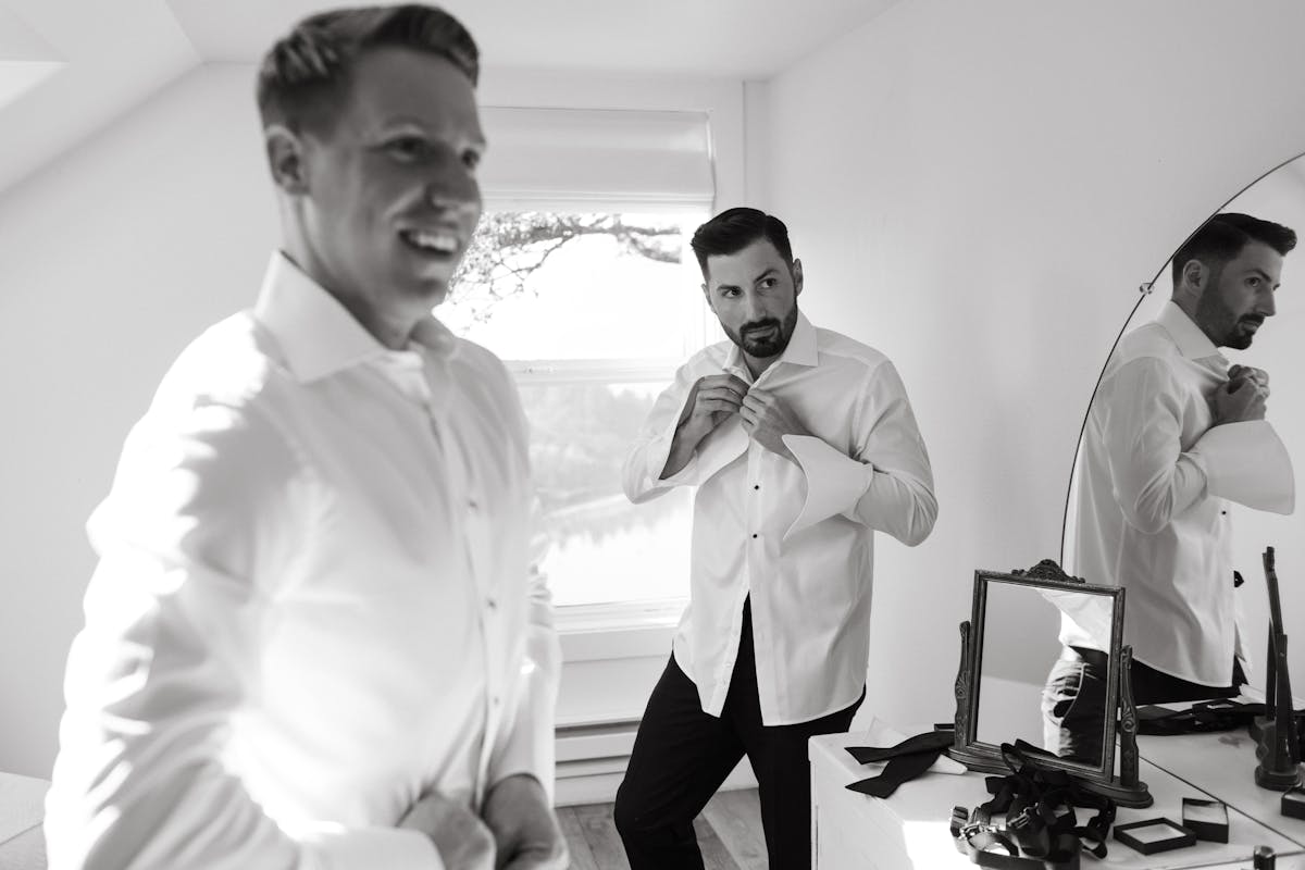 Guys getting ready buttoning men's dress shirts over their undershirts for a wedding.