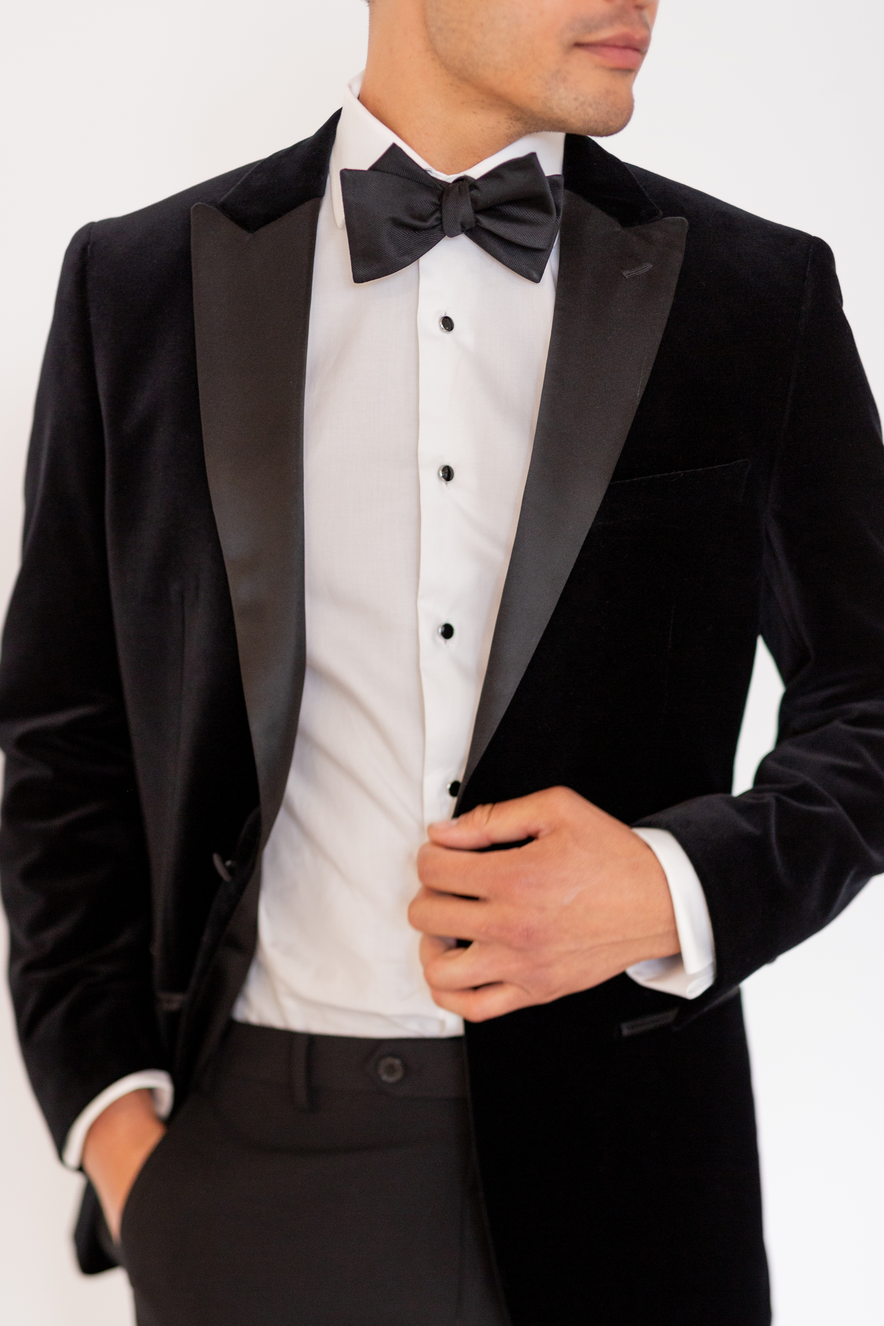 Details of a men's black velvet tuxedo outfit with a bowtie and French cuffs